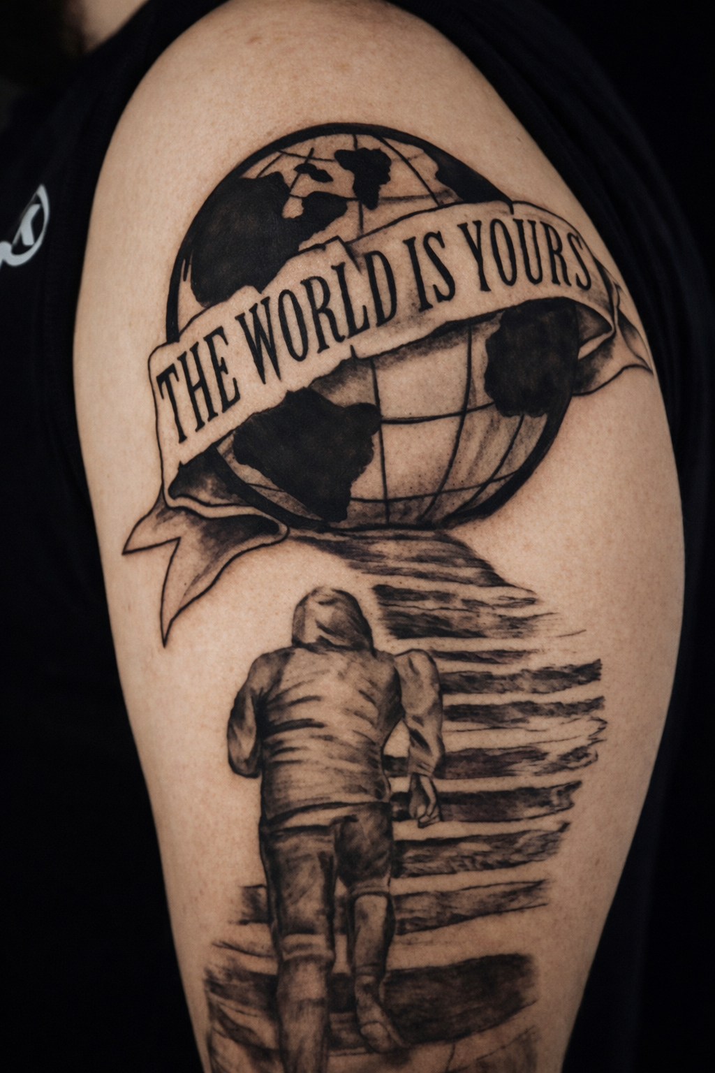 “The World Is Yours” black and grey realism tattoo symbolizing ambition, movement, and limitless opportunity — tattooed by Brass Knuckles Ink in Bronx, NY specializing in meaningful, story-driven tattoo designs