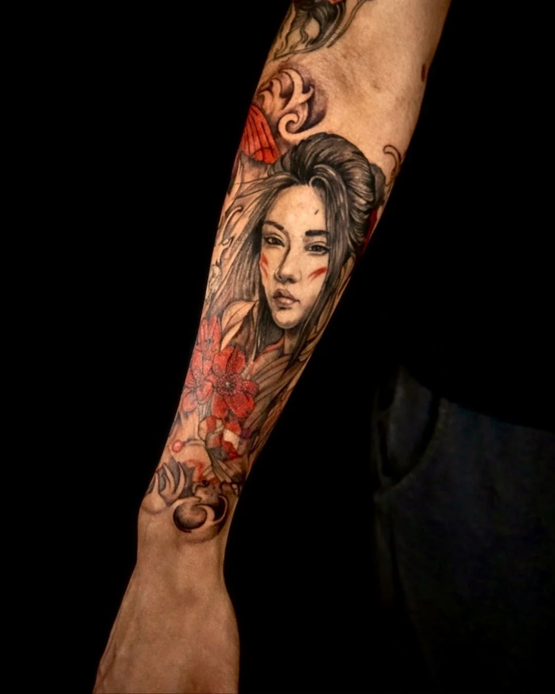 This geisha portrait sleeve tattoo features black and grey realism with soft red accents and flowing ornamental elements, creating a timeless and elegant composition. Crafted by professional tattoo artists in the Bronx, NYC for collectors seeking lux