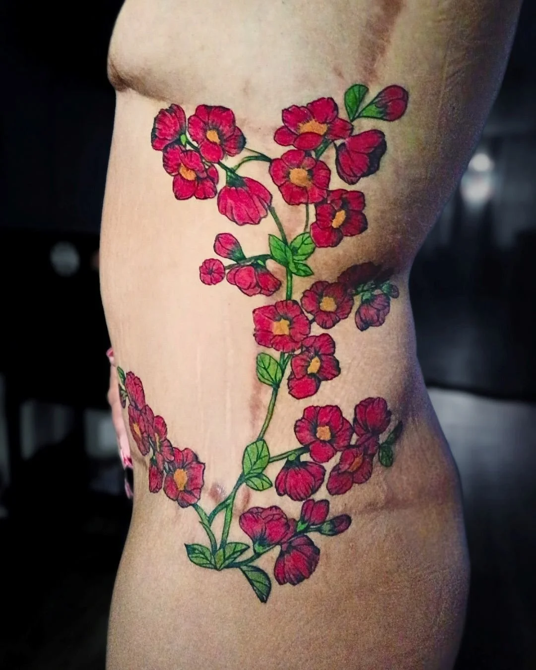 Scar camouflage floral side tattoo with red flowers by Brass Knuckles Ink Tattoo Studio