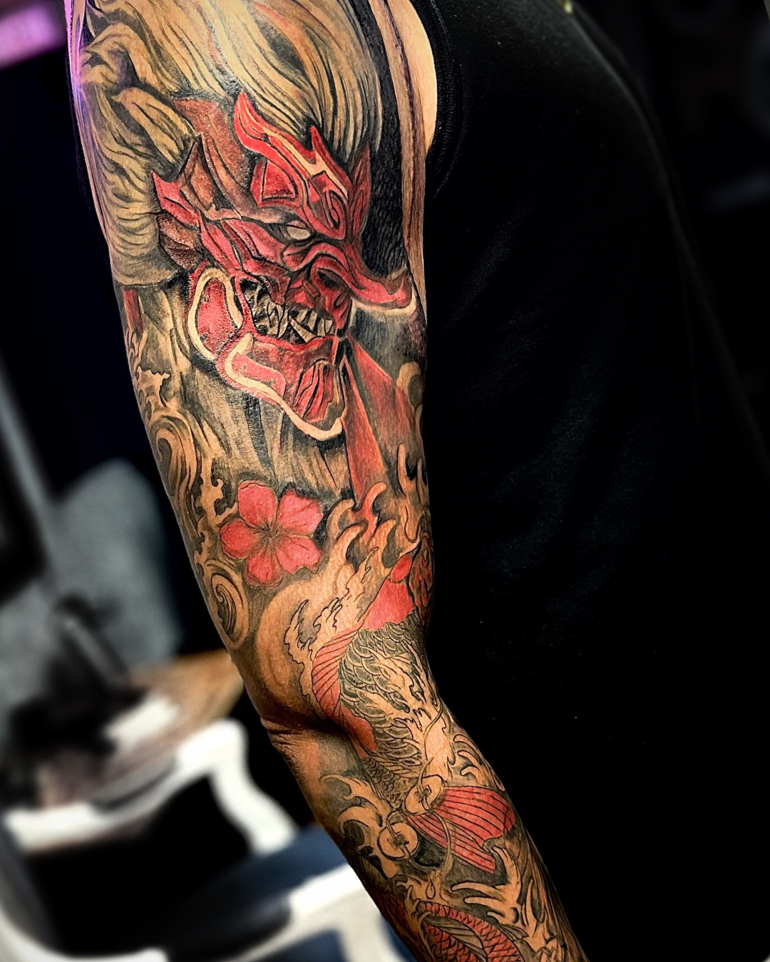 Japanese koi sleeve tattoo with an Oni mask symbolizing protection and strength, created by a professional Bronx NYC tattoo studio.