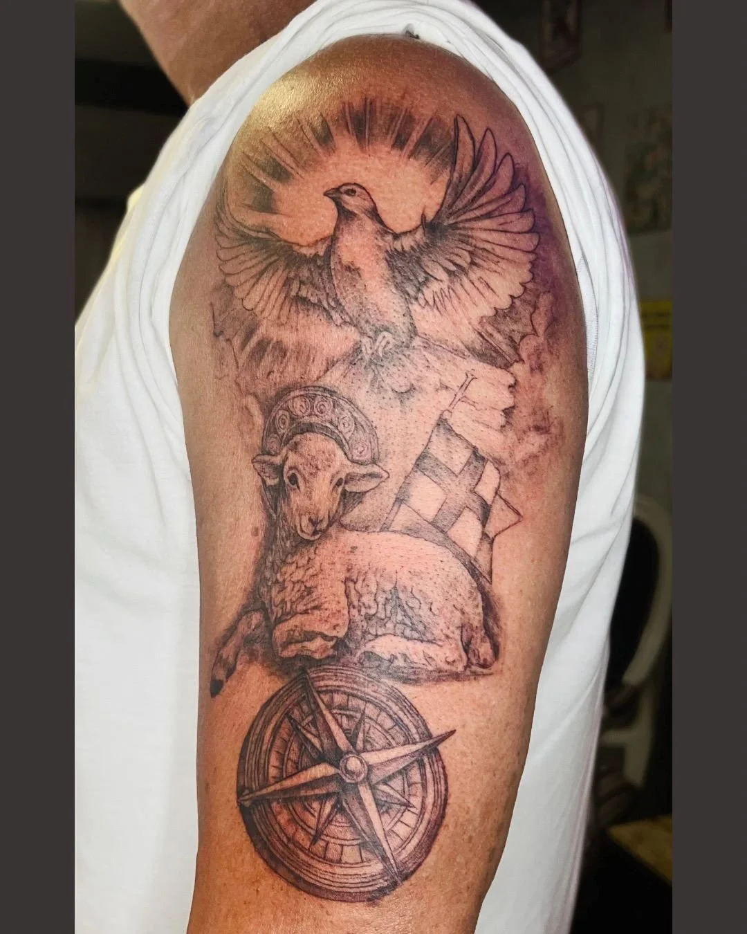 Christian sleeve tattoo featuring lamb, dove, cross flag and compass by Brass Knuckles Ink. High-end black and grey custom tattoos.