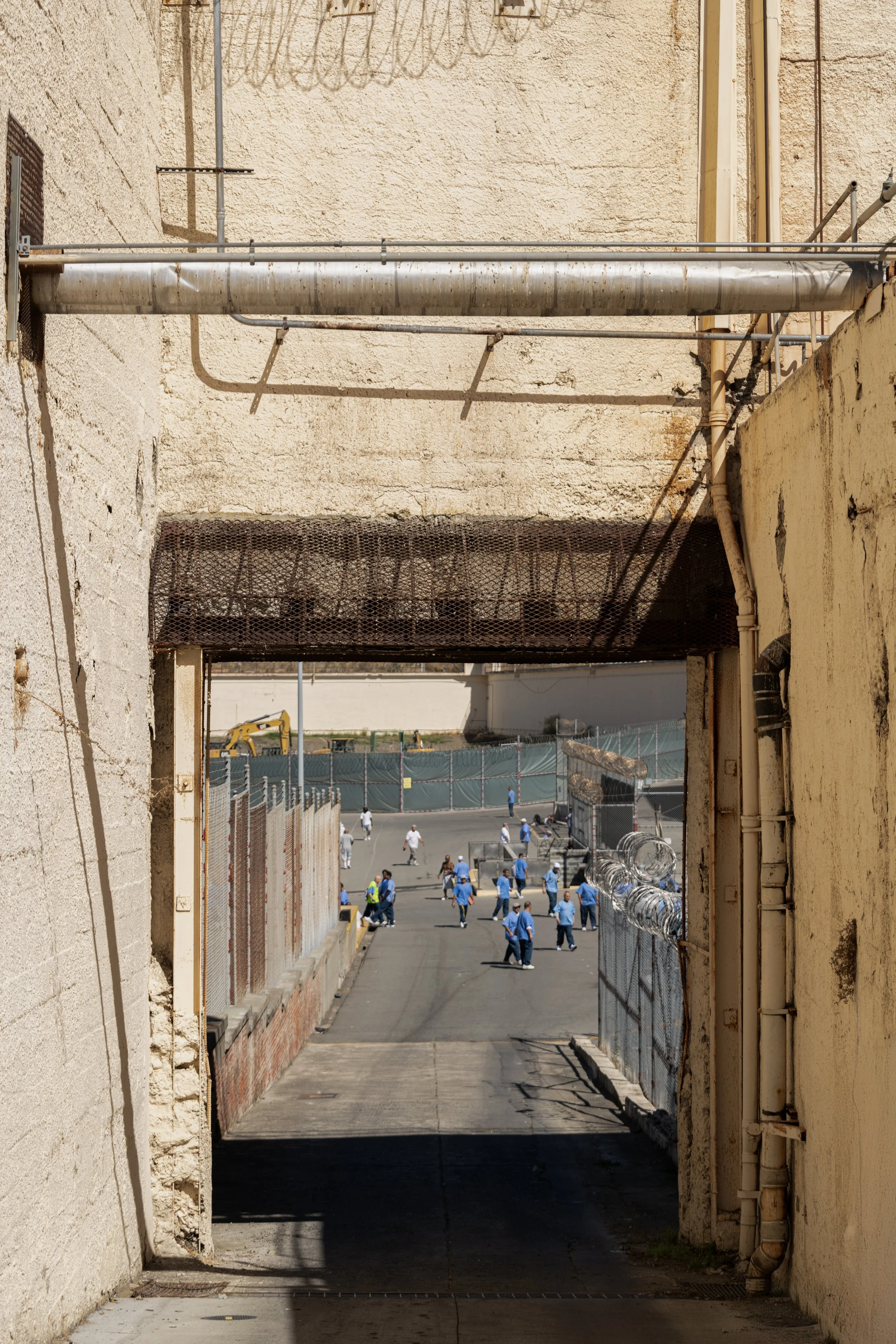A view through a narrow archway of a street scene with people walking. The photo is taken from inside a building looking out.