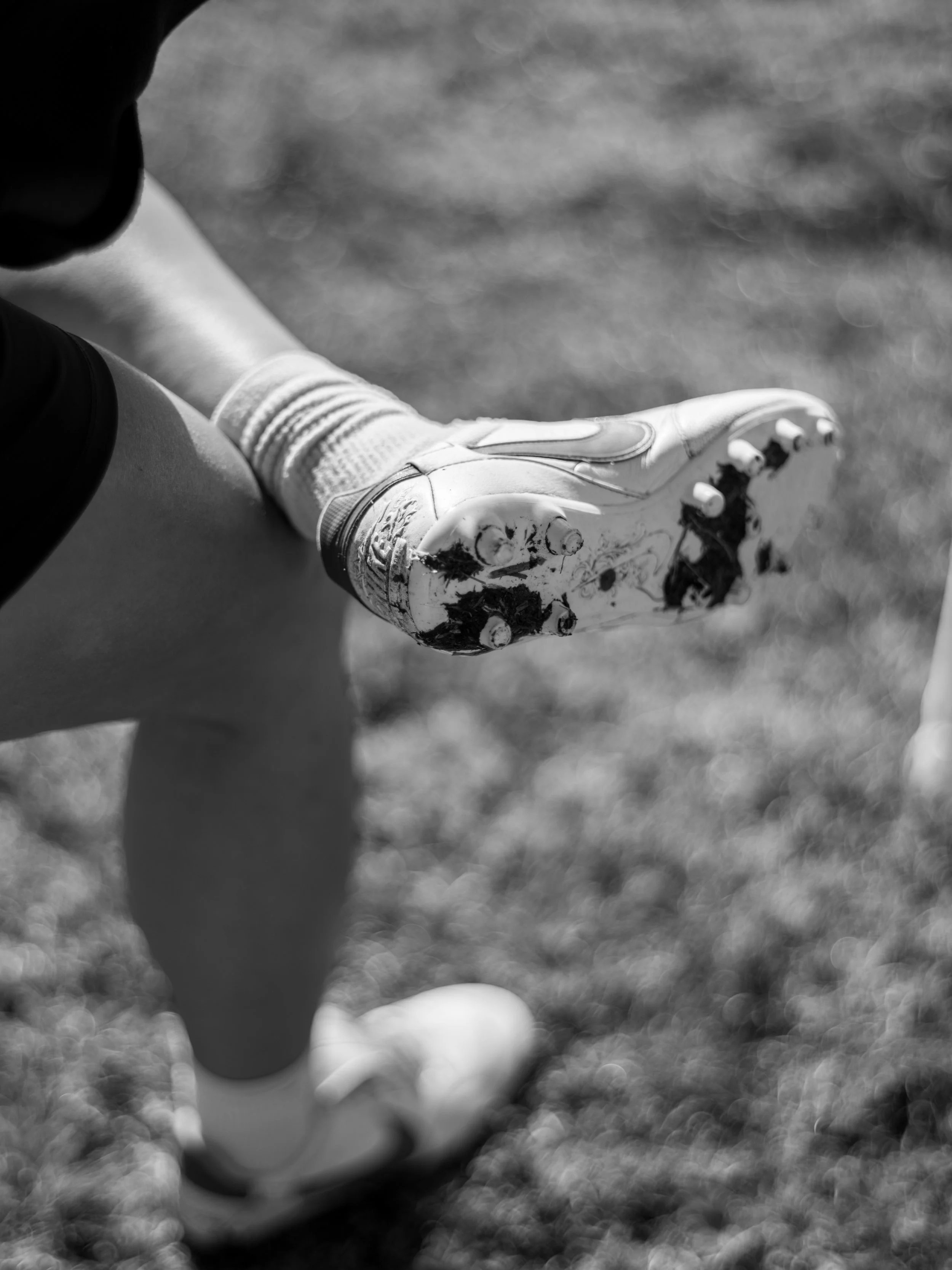 Close-up of a child's foot in a soccer cleat on a grassy field.