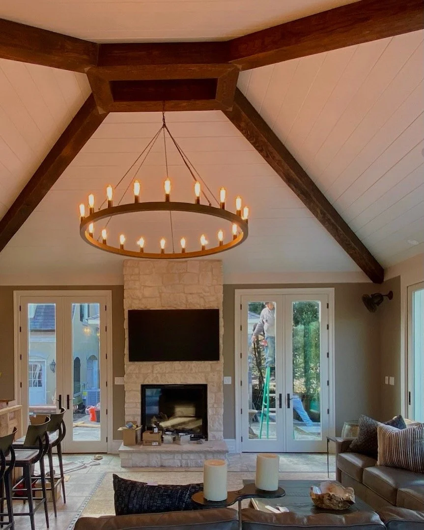 Finished living room with exposed wood beams, vaulted ceiling, and a stone fireplace.