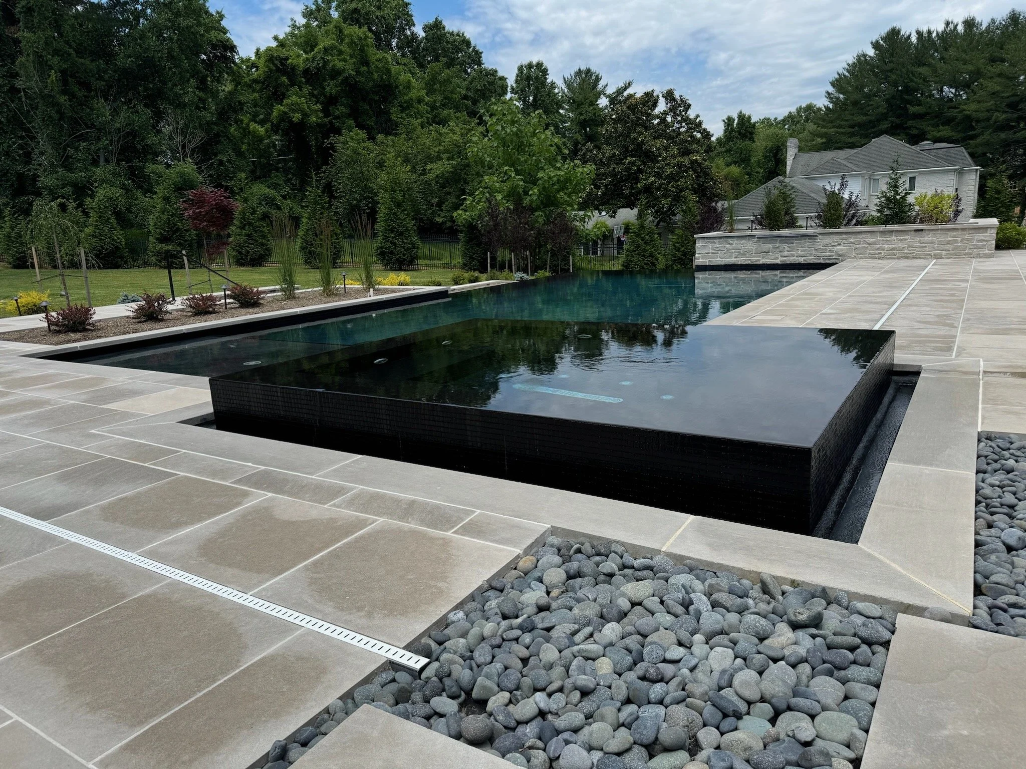 Custom pool with a raised spa, stone patio and masonry water feature.