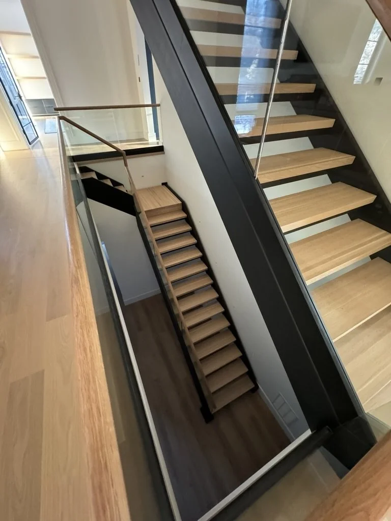Steel stair framing, timber treads and glass balustrades bring structure and finish together.