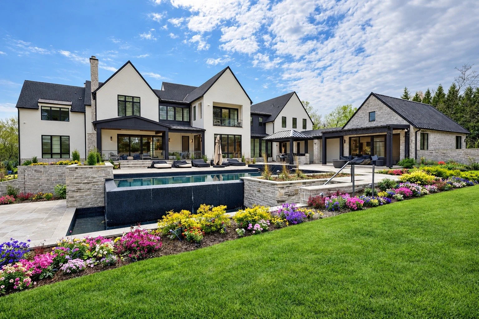 A completed custom home with a pool, stone terraces and integrated outdoor living spaces.
