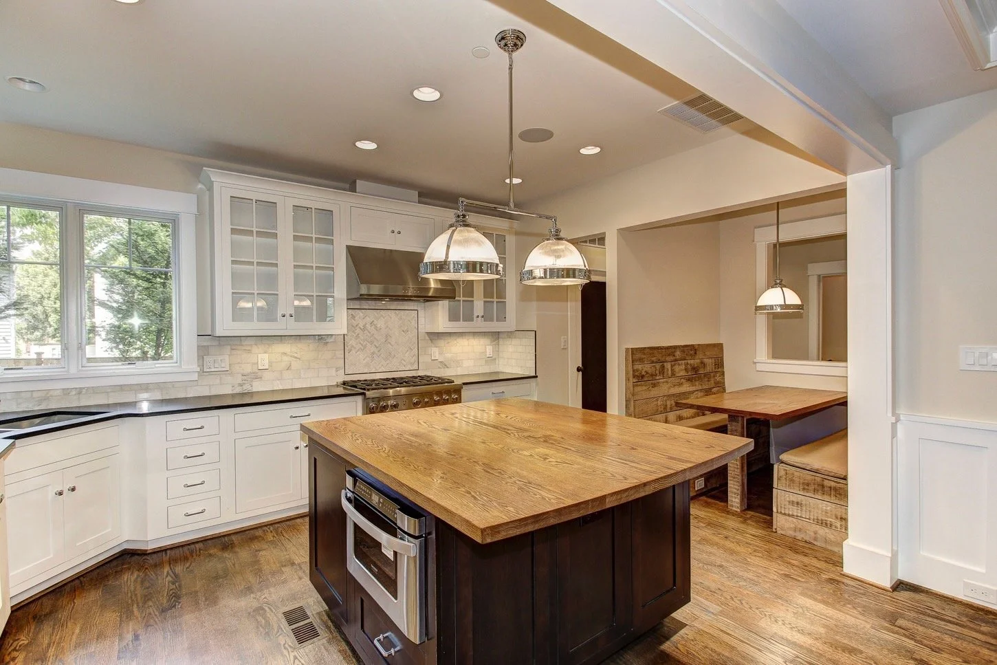 6604 Seven Locks Road: kitchen with white cabinetry, wood-topped island, and pendant lighting.