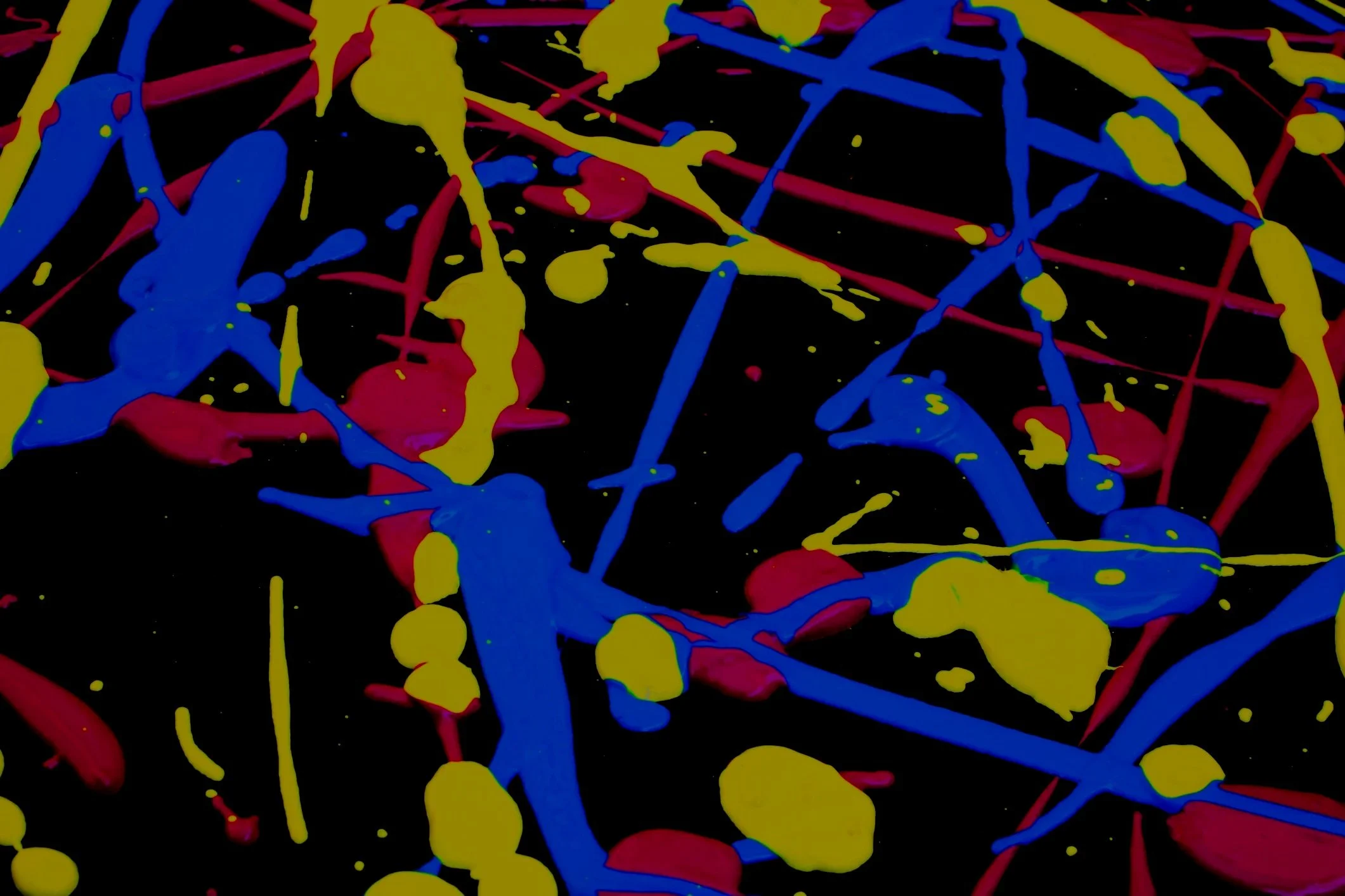 Abstract paint splatter on black background with yellow, blue, and red colors