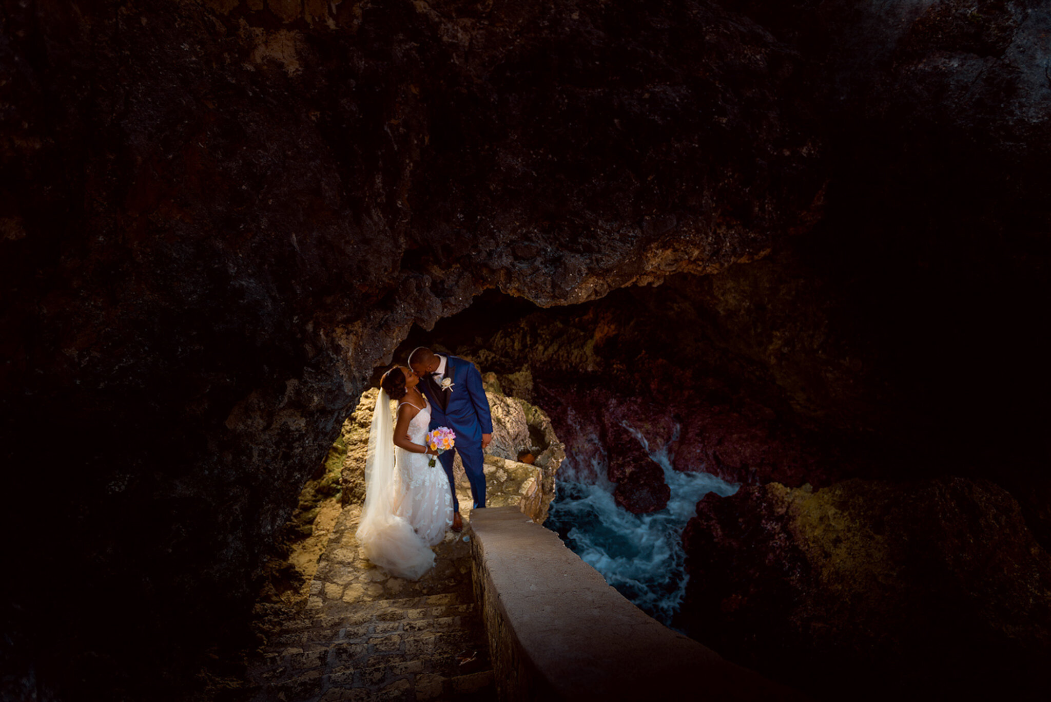 bride and groom under dark moody cave at water little waters negril, jamaica