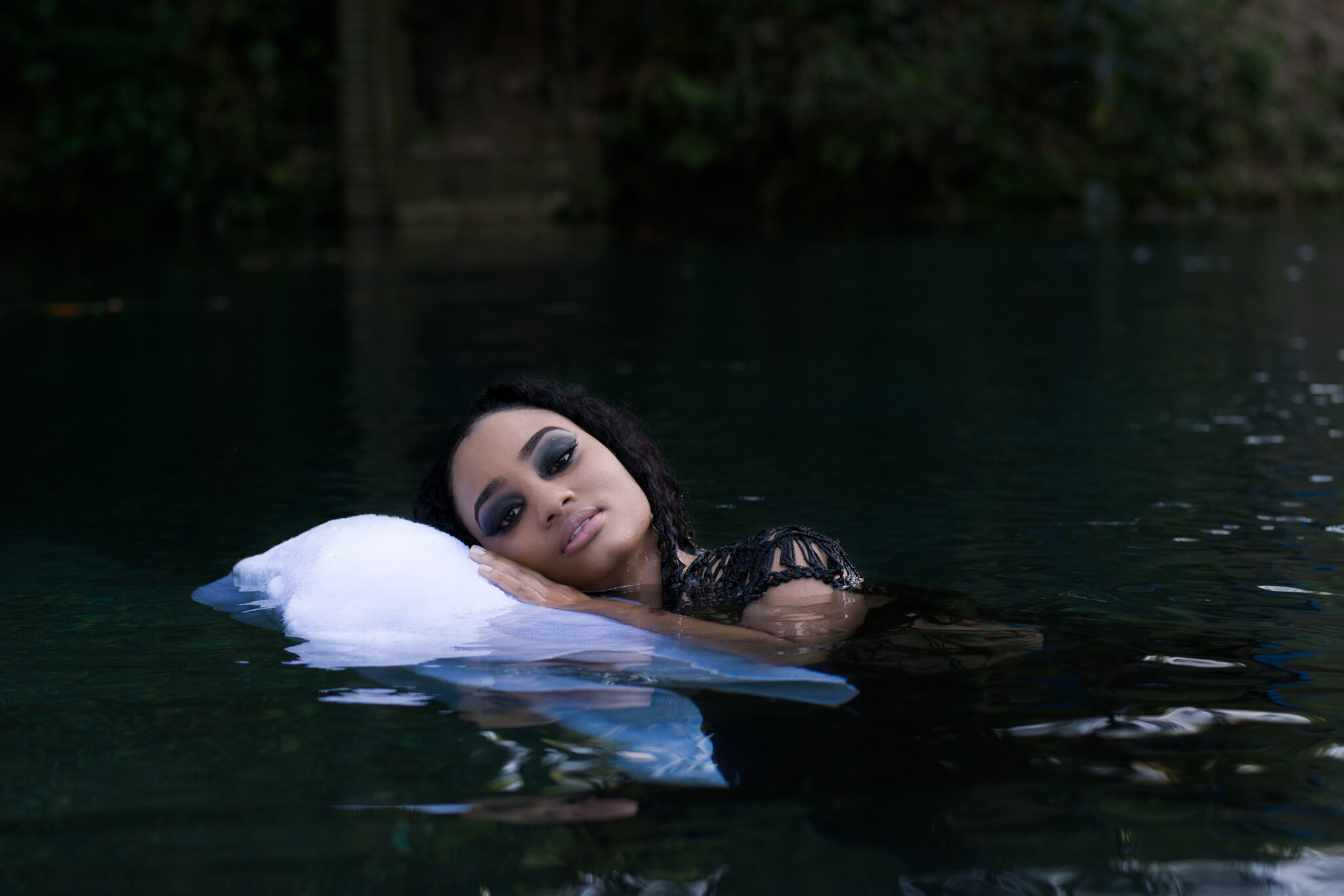 dark conceptual photoshoot with girl laying on a pillow in the water
