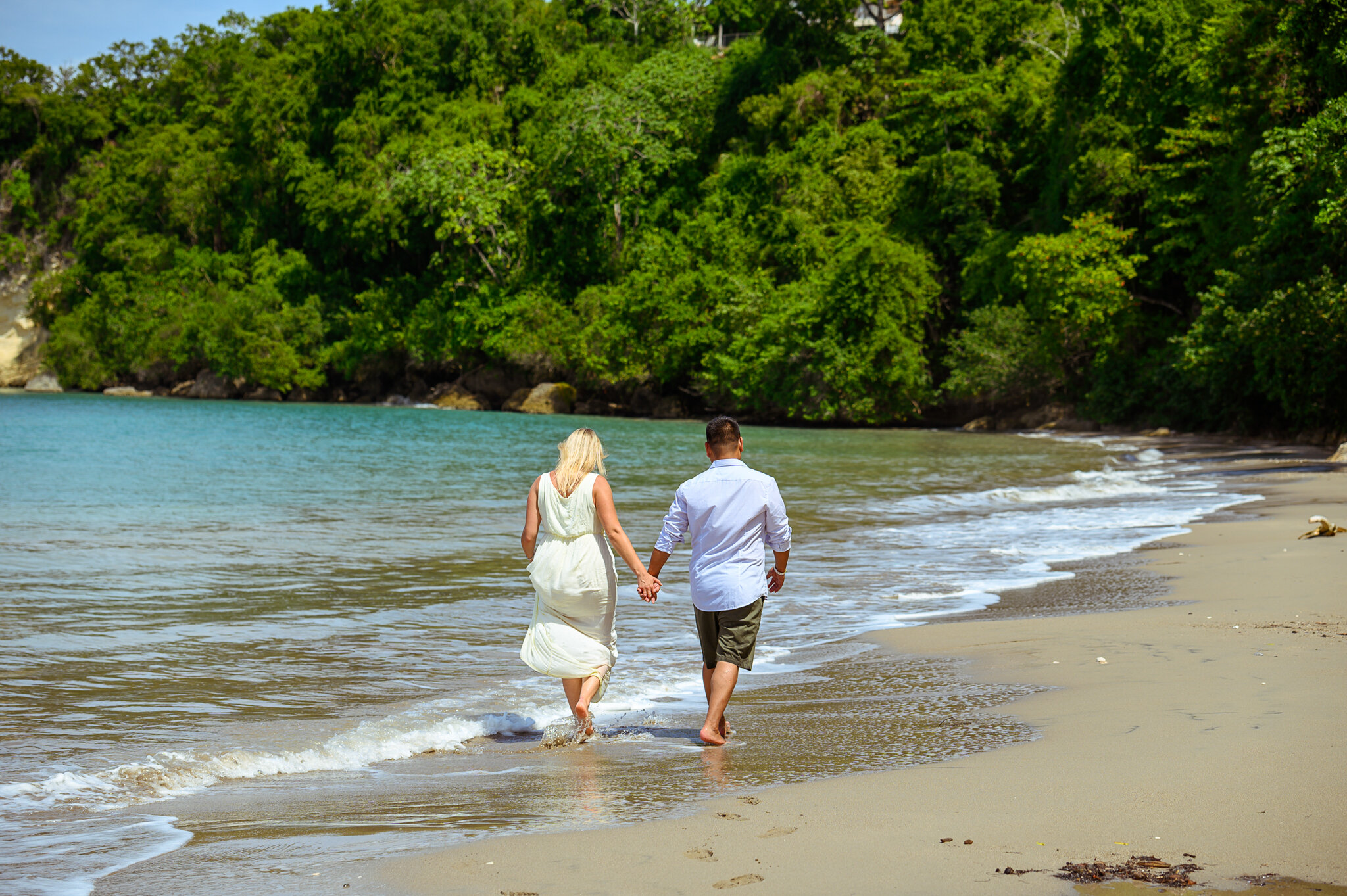 bride and groom holding hands walking on beach 