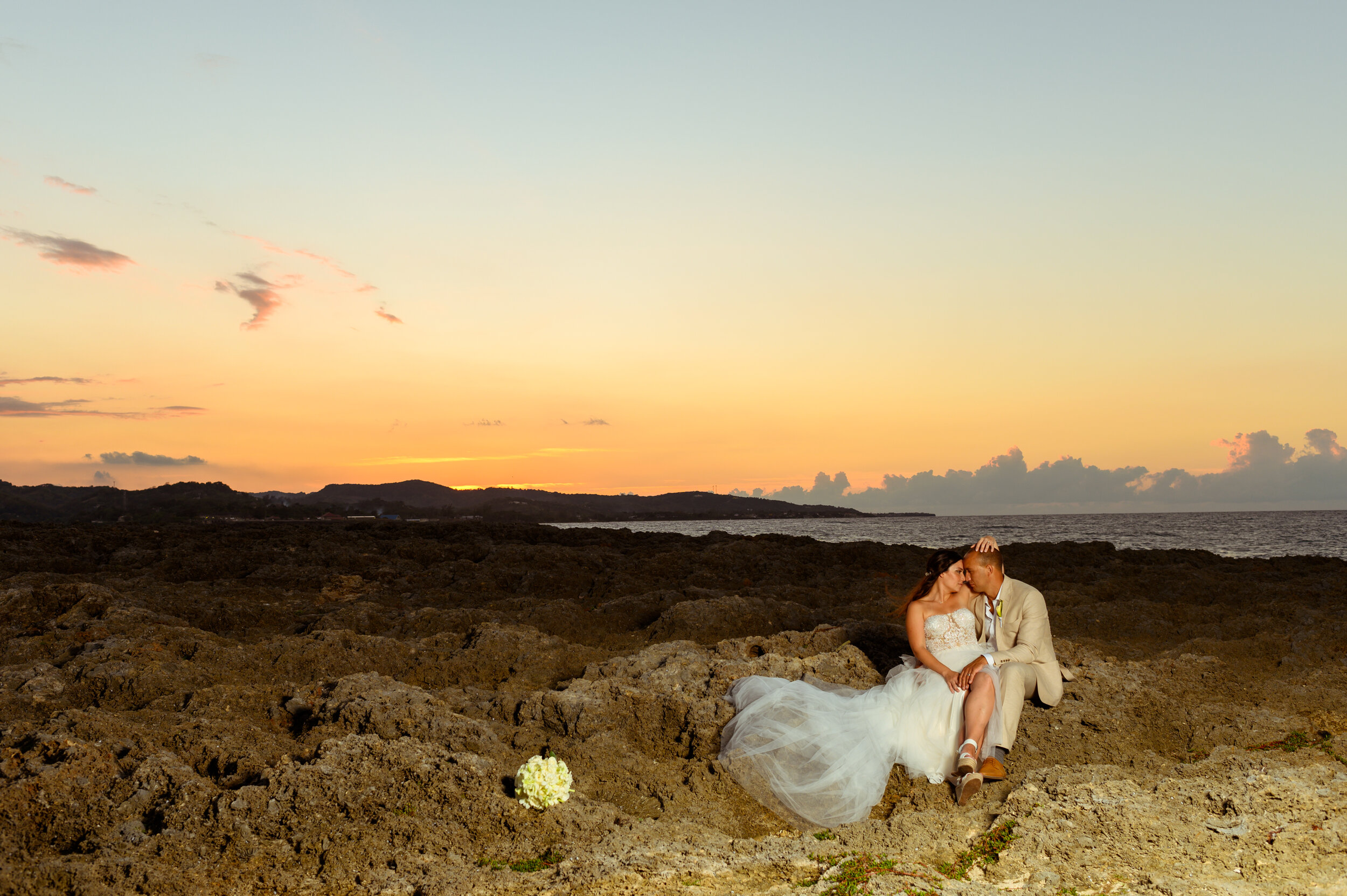 bride and groom kissing on rocks in sunset grand palladium lady hamilton