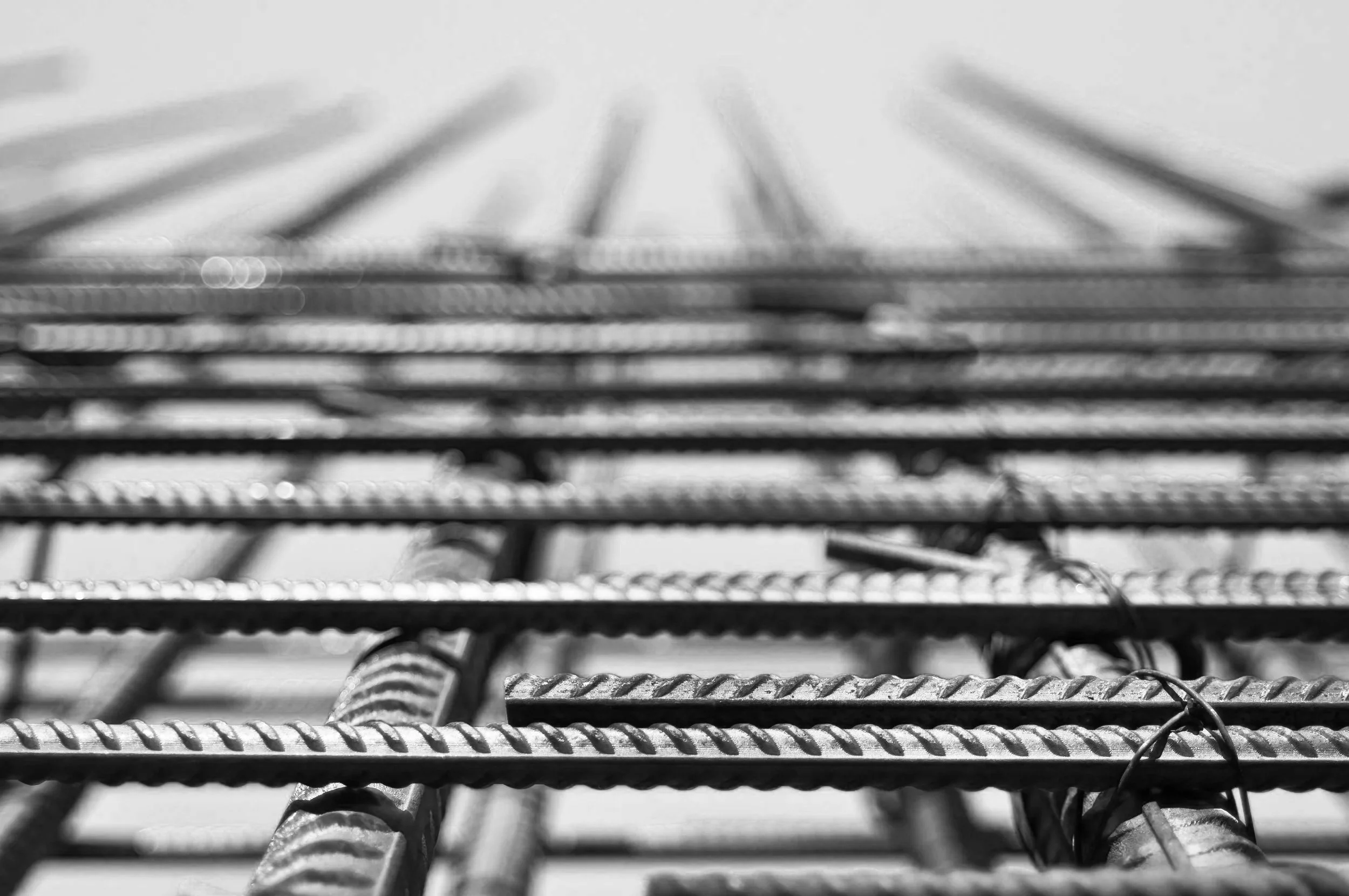 Layered steel reinforcement bars viewed in close detail, representing hidden forces and structural systems used in gunite pool and architectural and landscape construction in Gabriel Messuti’s work