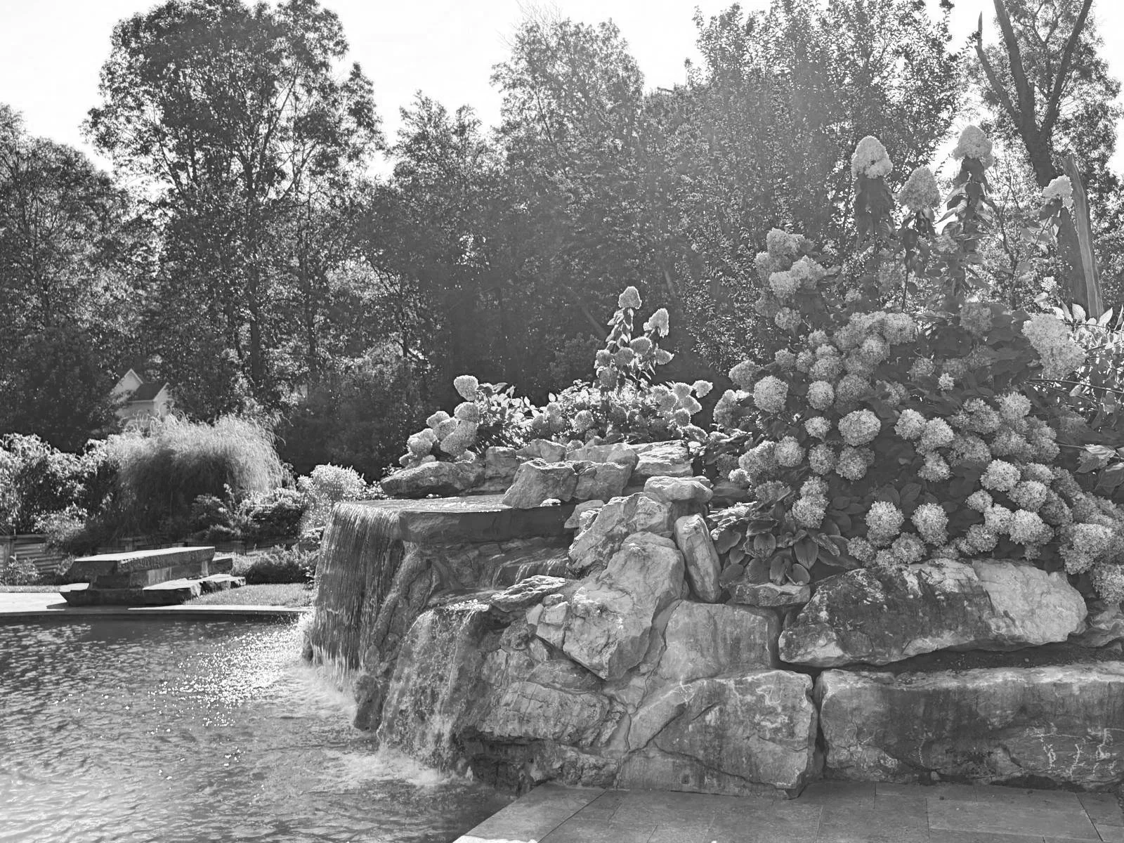 Custom stone waterfall integrated into a landscape and pool environment by Messuti, where engineered systems resolve into a calm outdoor experience.