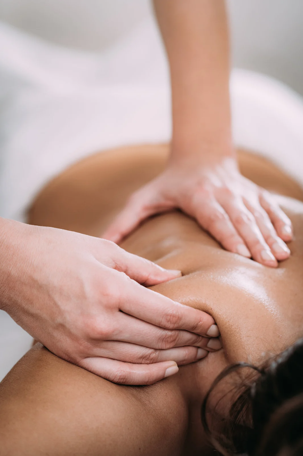 A massage therapist massages a woman's shoulder.