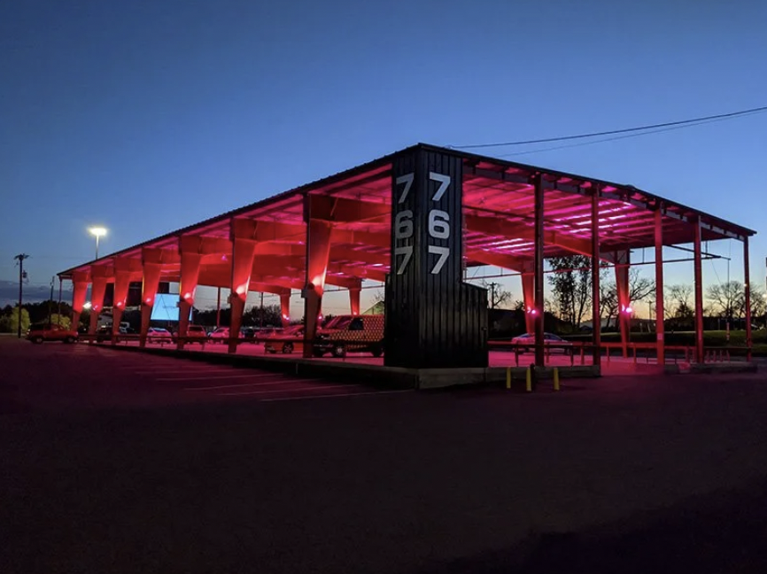 A modern, open parking structure illuminated with pink lighting. The location of Glimmer - the pop-up drive-in created by Kris Growcott.
