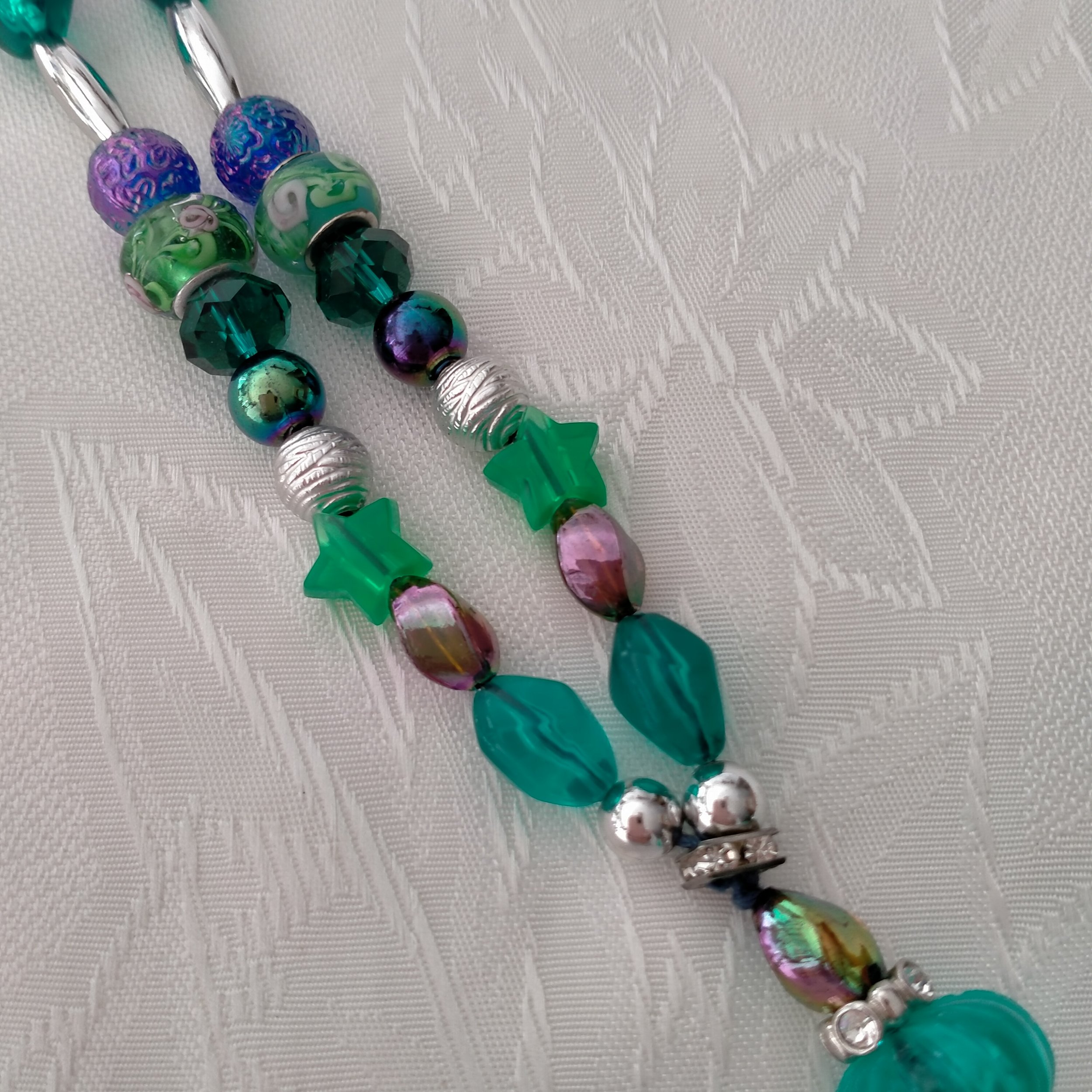 A beautiful necklace made using glass, crystal, acrylic, metal, resin and plastic beading. Several shades of greens with Crystal Rhinestones, Rondelle beads with Roses and Acrylic Stars
