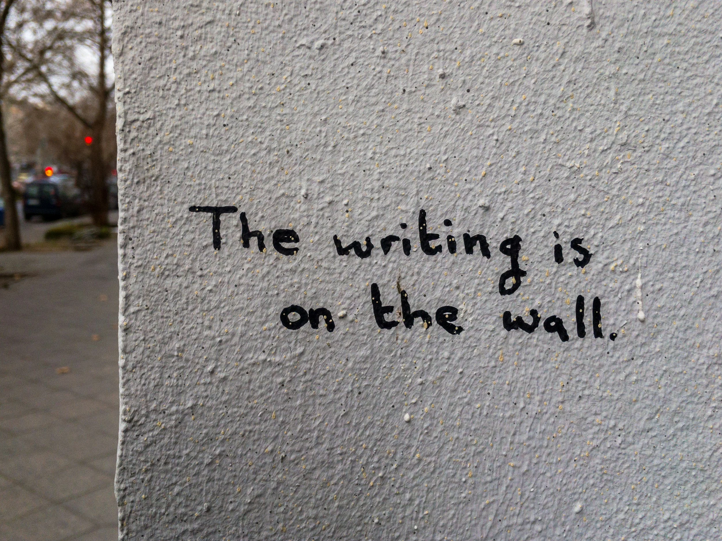 A wall with the handwritten phrase 'The writing is on the wall.'