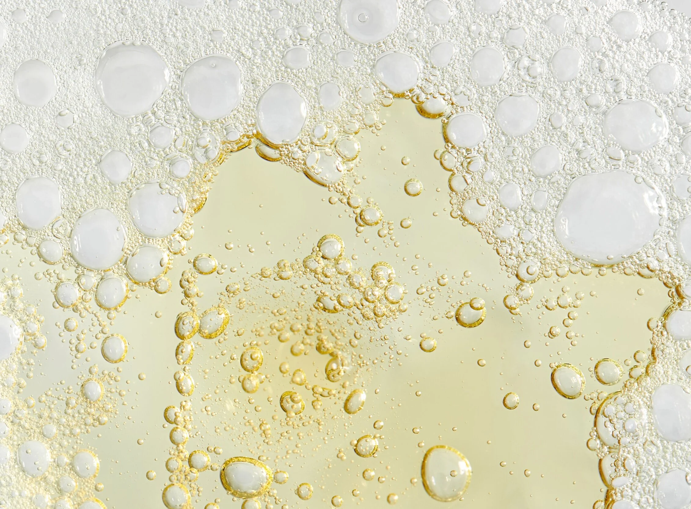 A close-up view of effervescent bubbles in a light-colored carbonated beverage.