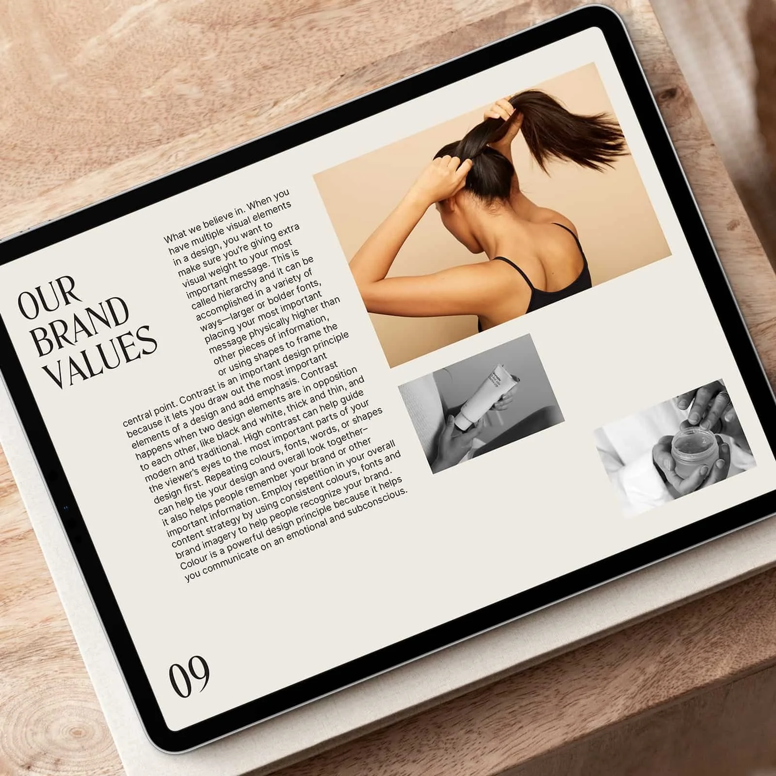 A tablet displaying an article with images, placed on a wooden surface. The article includes text about brand values and a suit of images showing a woman adjusting her hair, a hand holding a tube of skincare, and hands holding a jar of cream.