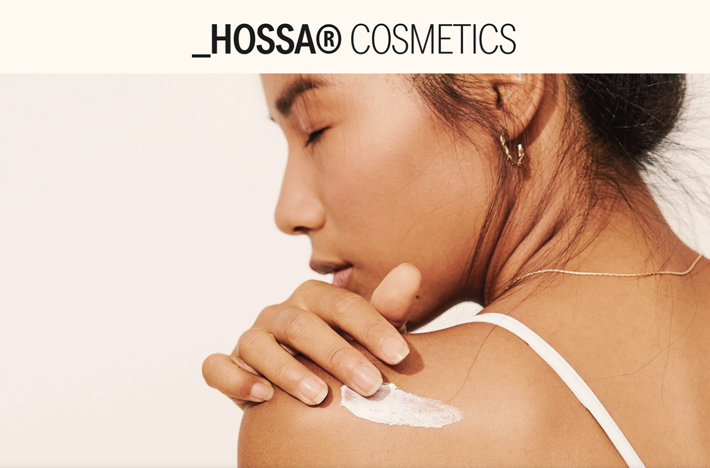 A woman with closed eyes applying white cream or lotion to her shoulder, promoting Hossa Cosmetics.