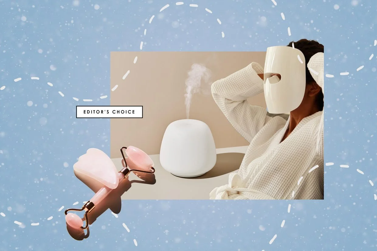 A woman in a robe wearing a mask, holding her head while a white diffuser emits steam, with a pink jade roller in front and a blue snowy background with white dashed lines and snowflakes. The label 'Editor's Choice' is present.