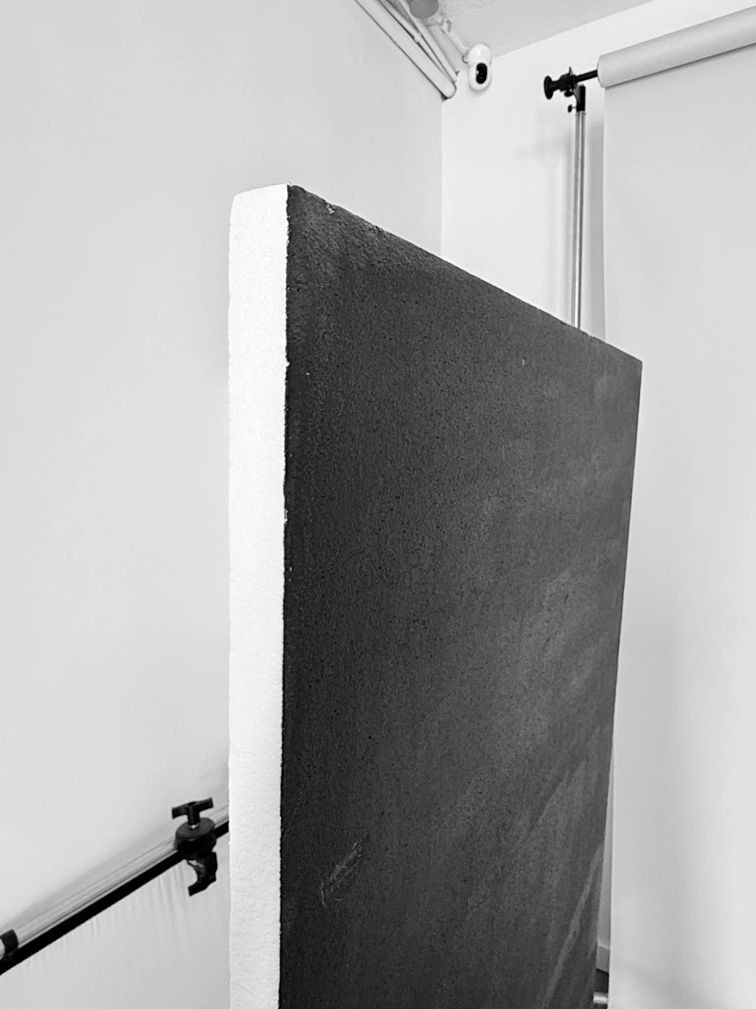 Image of a photography studio with a white backdrop, black textured foam board, a round overhead camera, and photography equipment.