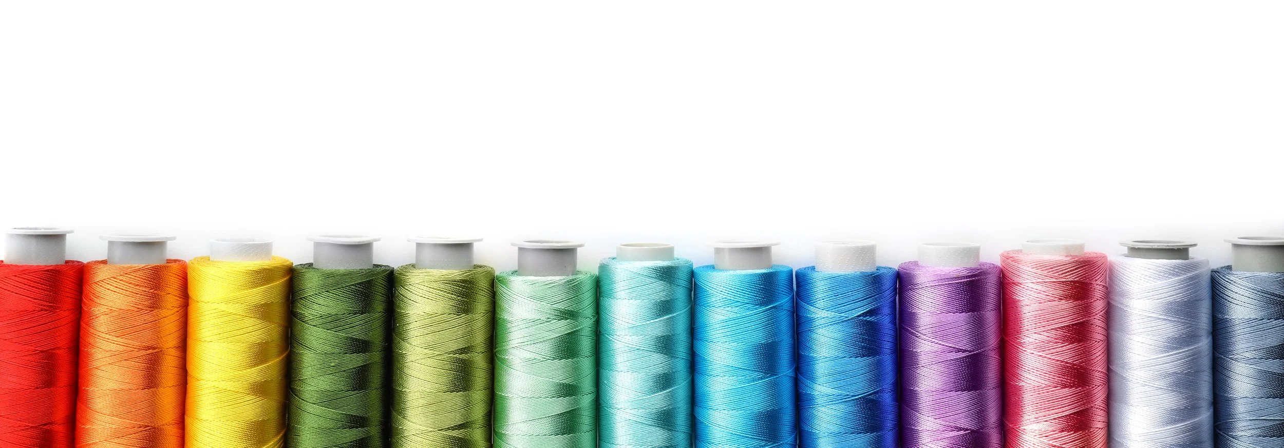 Colorful spools of thread arranged in a gradient from red to white.