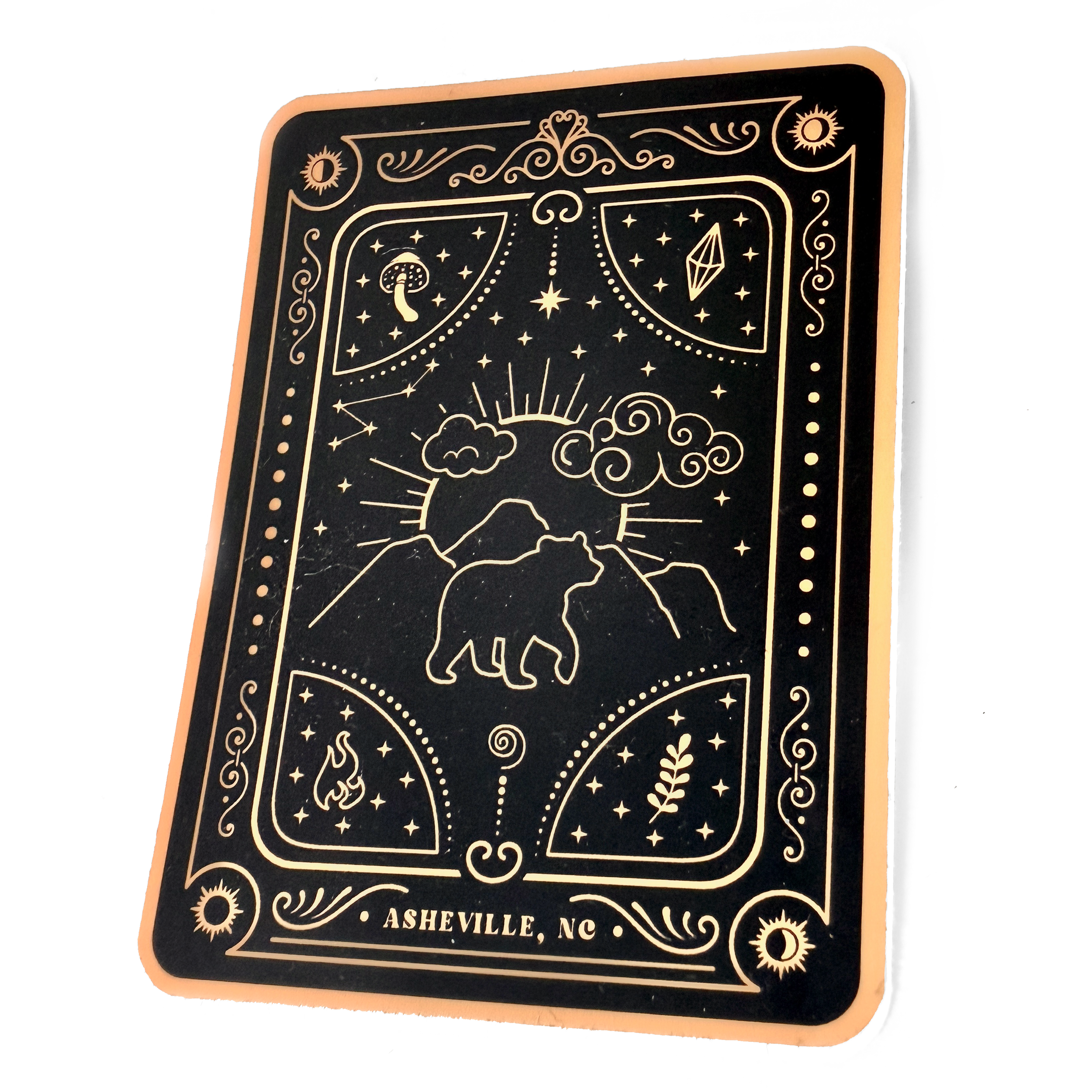 Close-up of a matte laminated sticker with celestial and nature motifs, reading Asheville, NC.