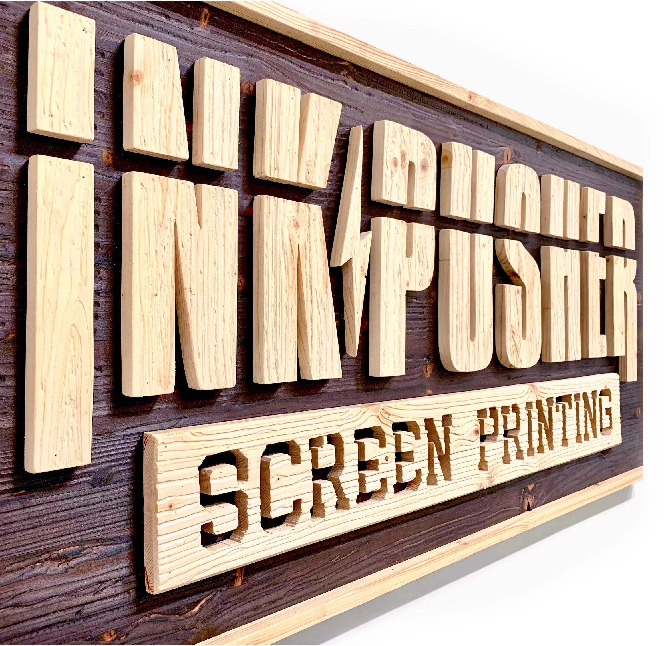 Wooden sign with carved letters mounted on dark wood background, with a light wood frame around the sign.