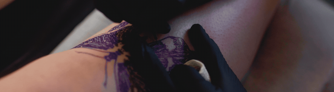 Close-up of a person's thigh with purple lace underwear and a black-gloved hand holding a camera or phone.