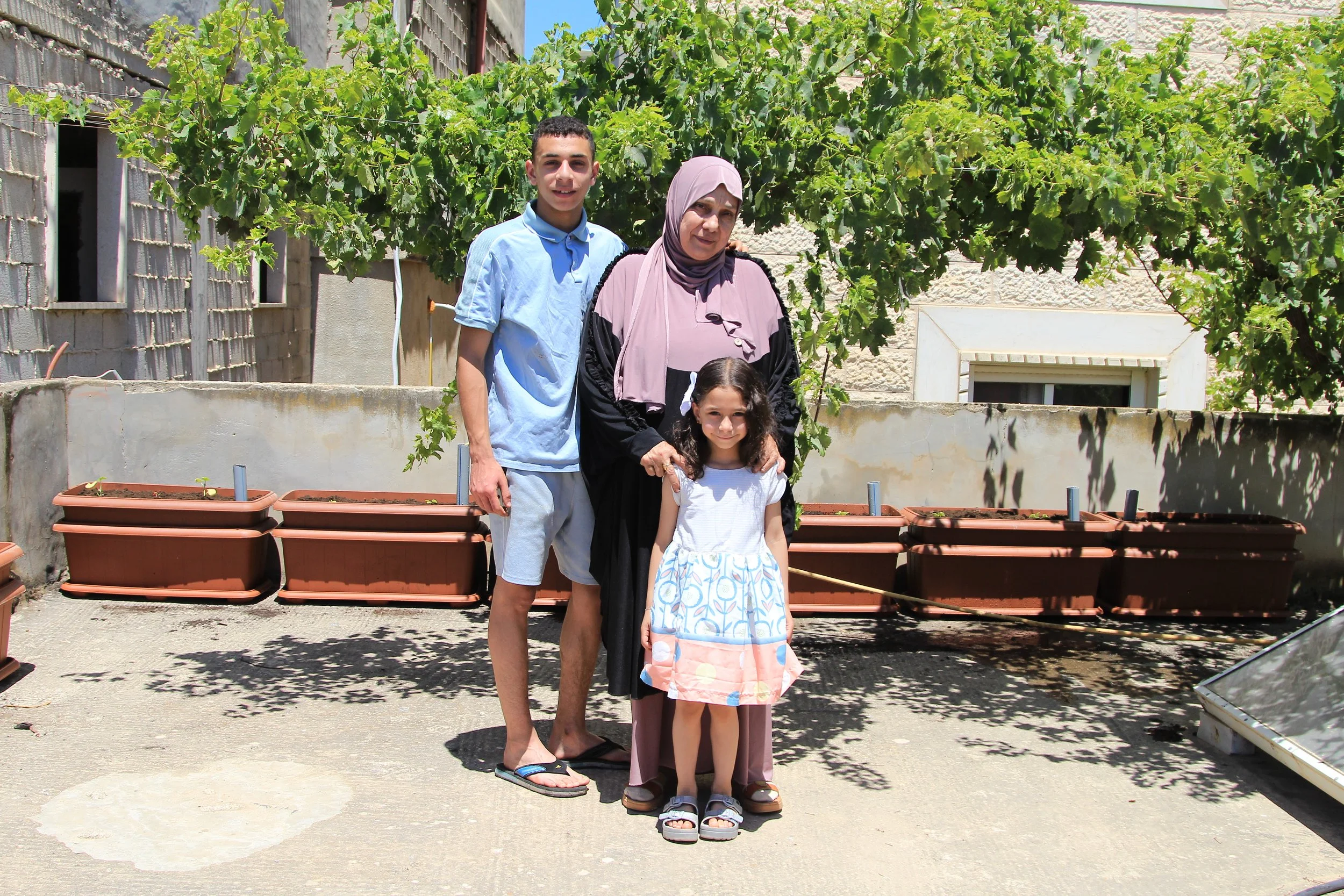 A family in the UN-run Aida camp hosting a garden with part of it behind them.
