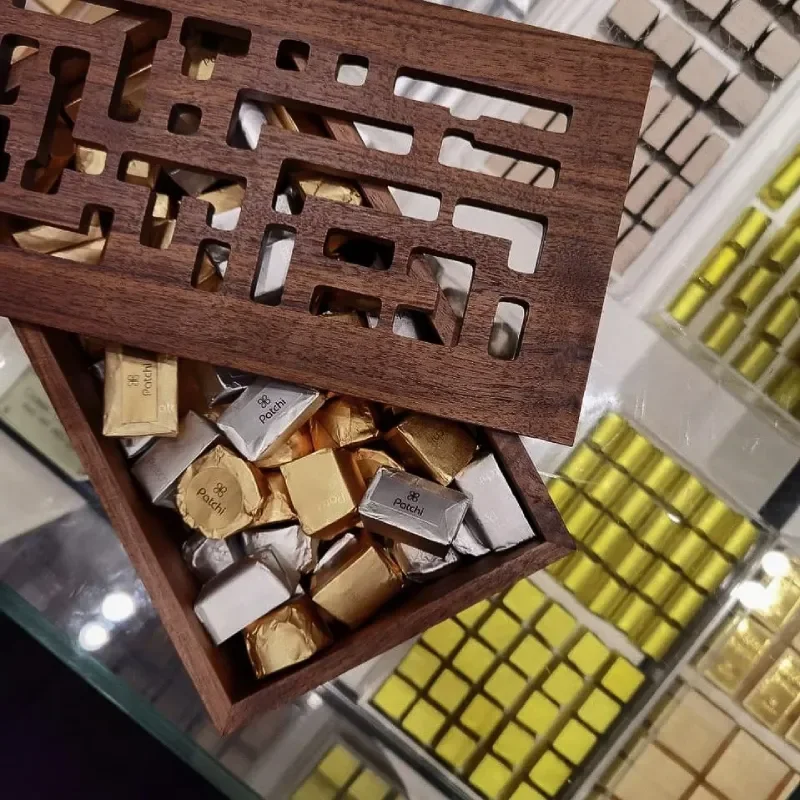 Wooden box with a geometric cutout lid filled with individually wrapped chocolates.