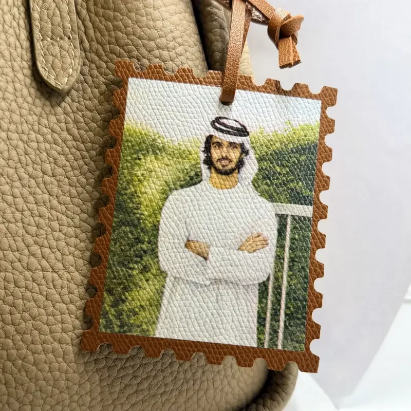 Leather bag tag featuring a portrait of an Emirati man in traditional white clothing.