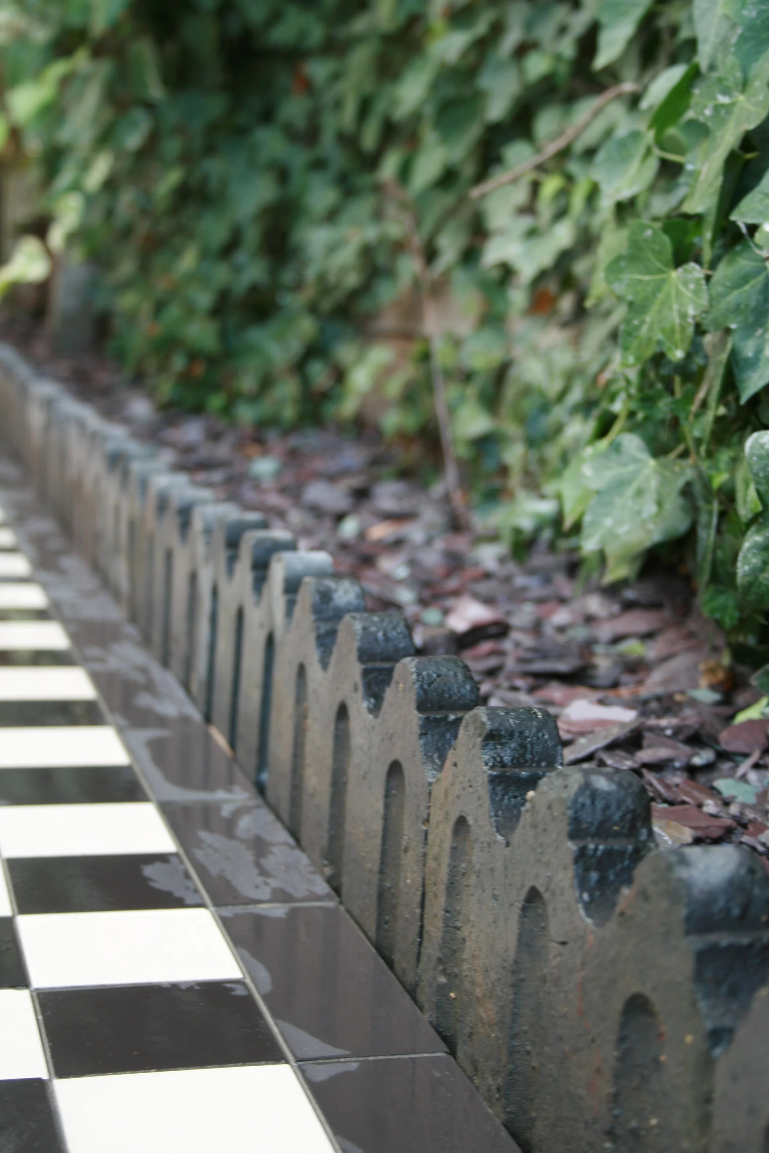 A close-up of a piano keyboard next to a decorative garden border with green foliage and brown mulch.