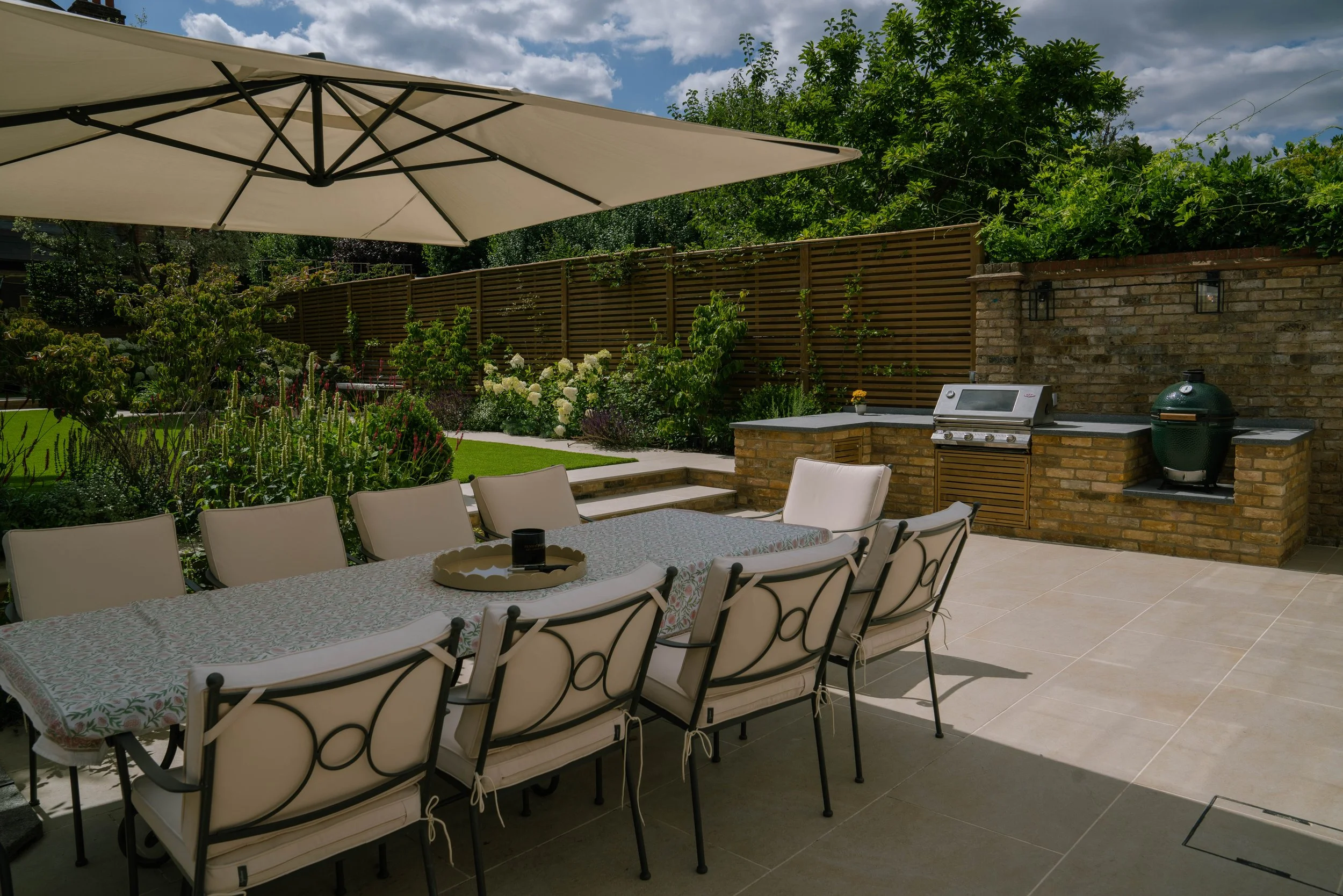 Modern outdoor kitchen built with reclaimed yellow London stock bricks and sleek porcelain paving by Harrington Brothers in a Wandsworth family garden