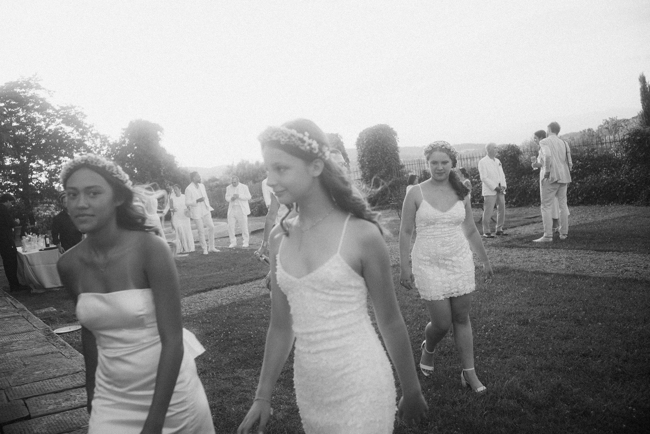 Junior bridesmaids dressed in white heading to the al fresco dinner reception at a wedding in Tuscany.