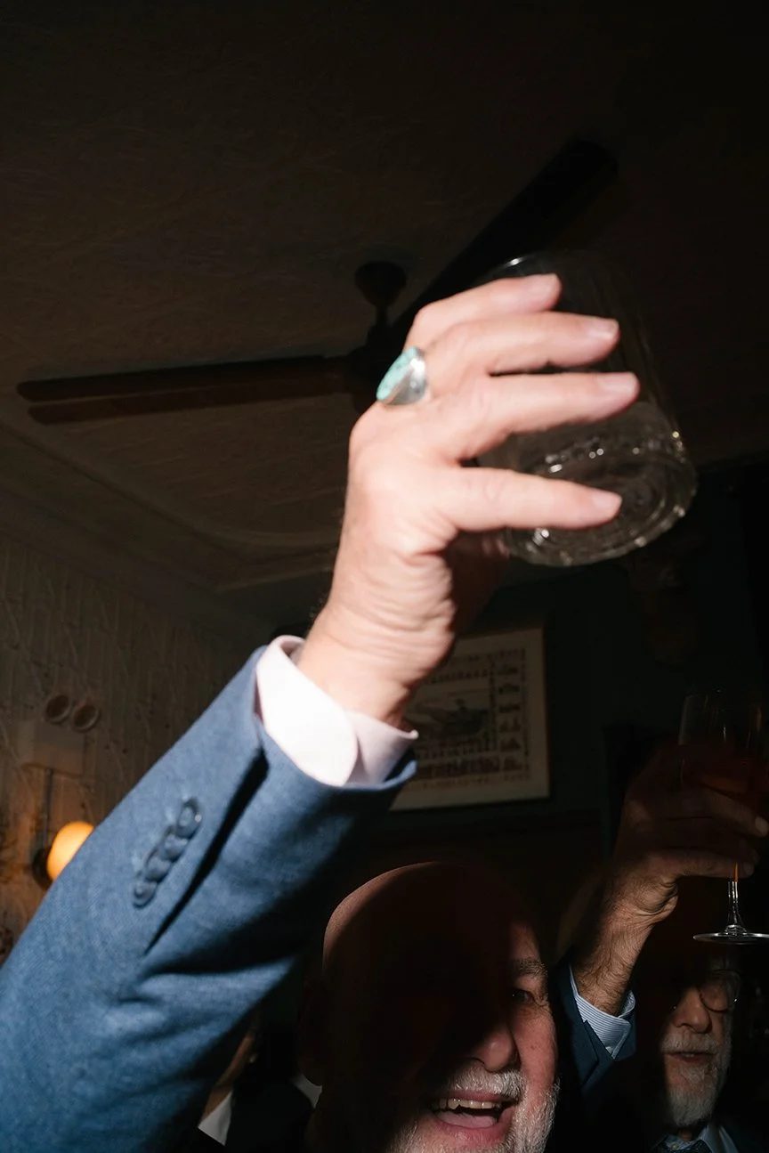 People celebrating indoors, raising glasses for a toast, smiling, and enjoying the moment.