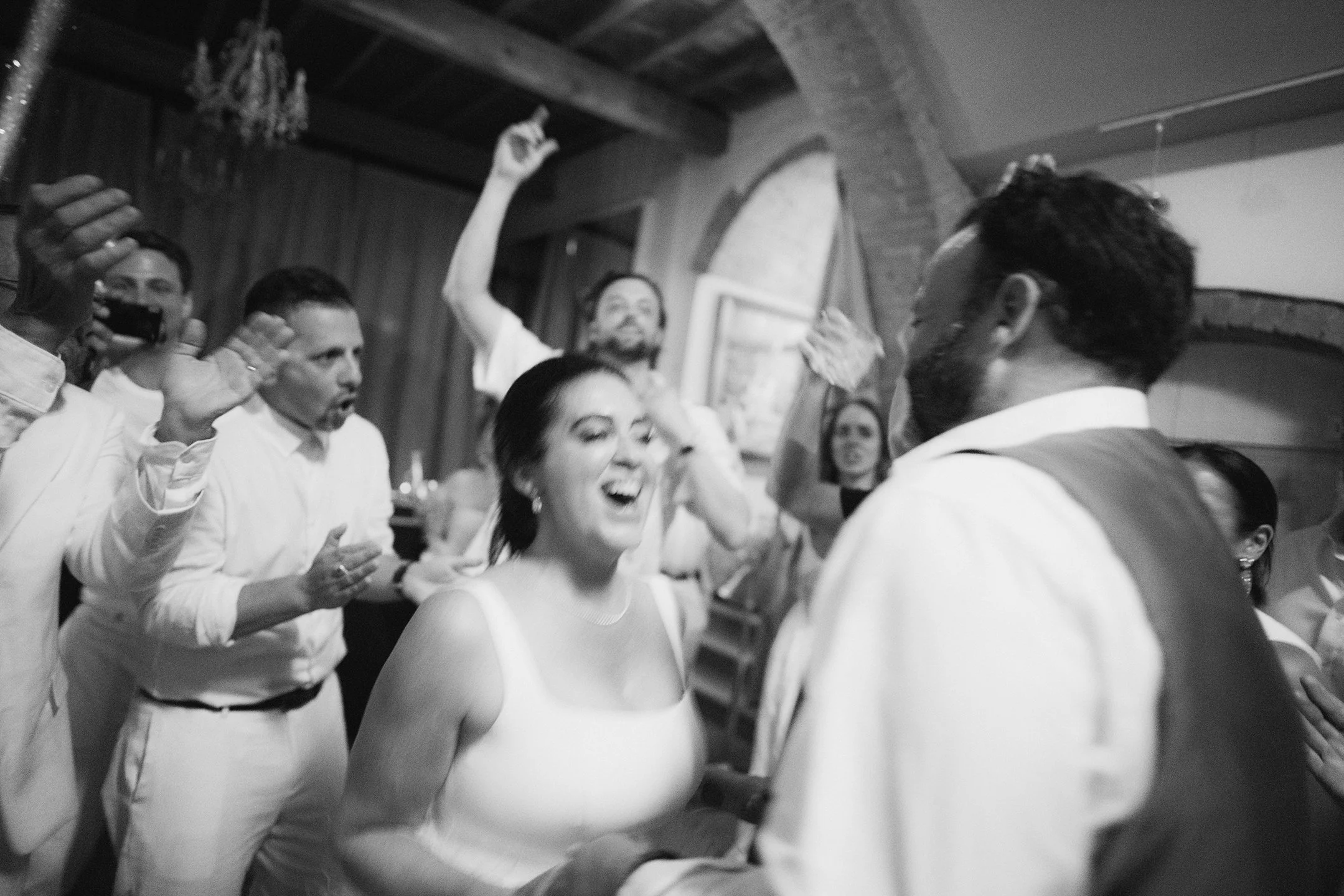 Bride and groom dancing with guests cheering them on at the after party of their Tuscan wedding at Villa Mangiacane.