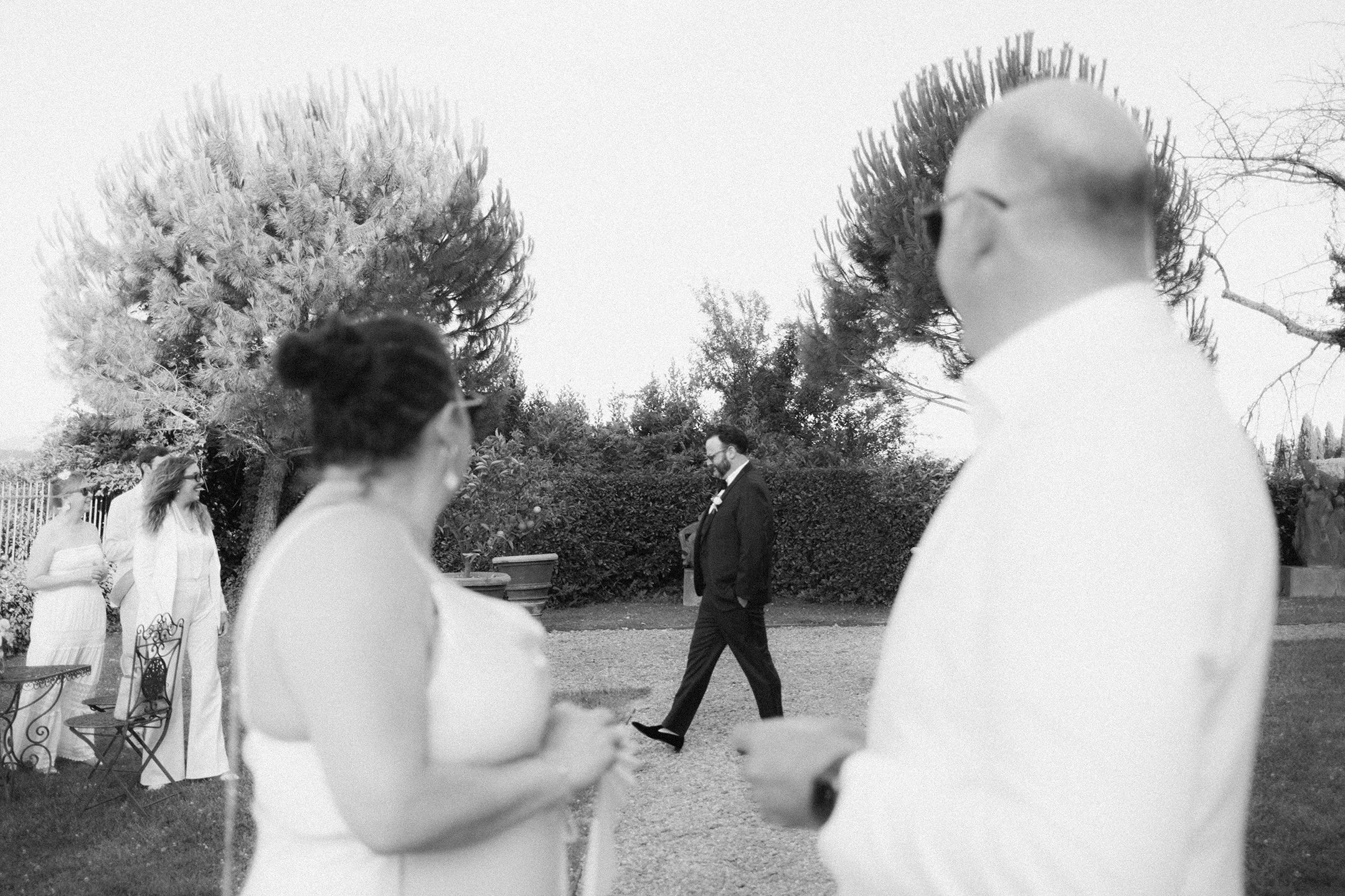 Groom walks to his ceremony as guests look on encouragingly at a tuscan wedding at Villa Mangiacane in Italy.