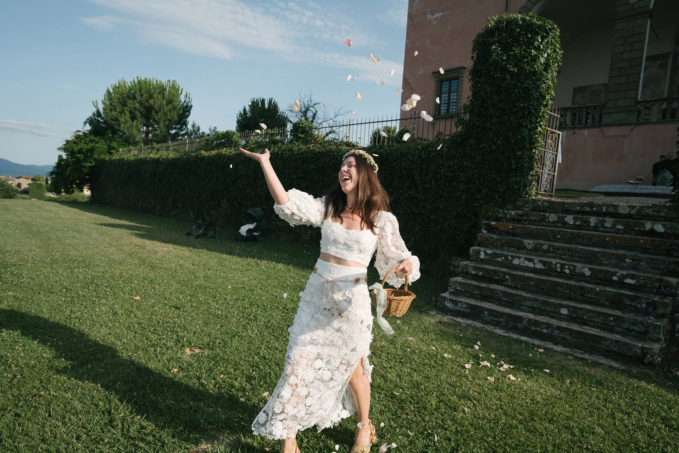 Maid of honor throwing flower petals from a basket as she walks down the aisle at a wedding in Tuscany at Villa Mangiacane.