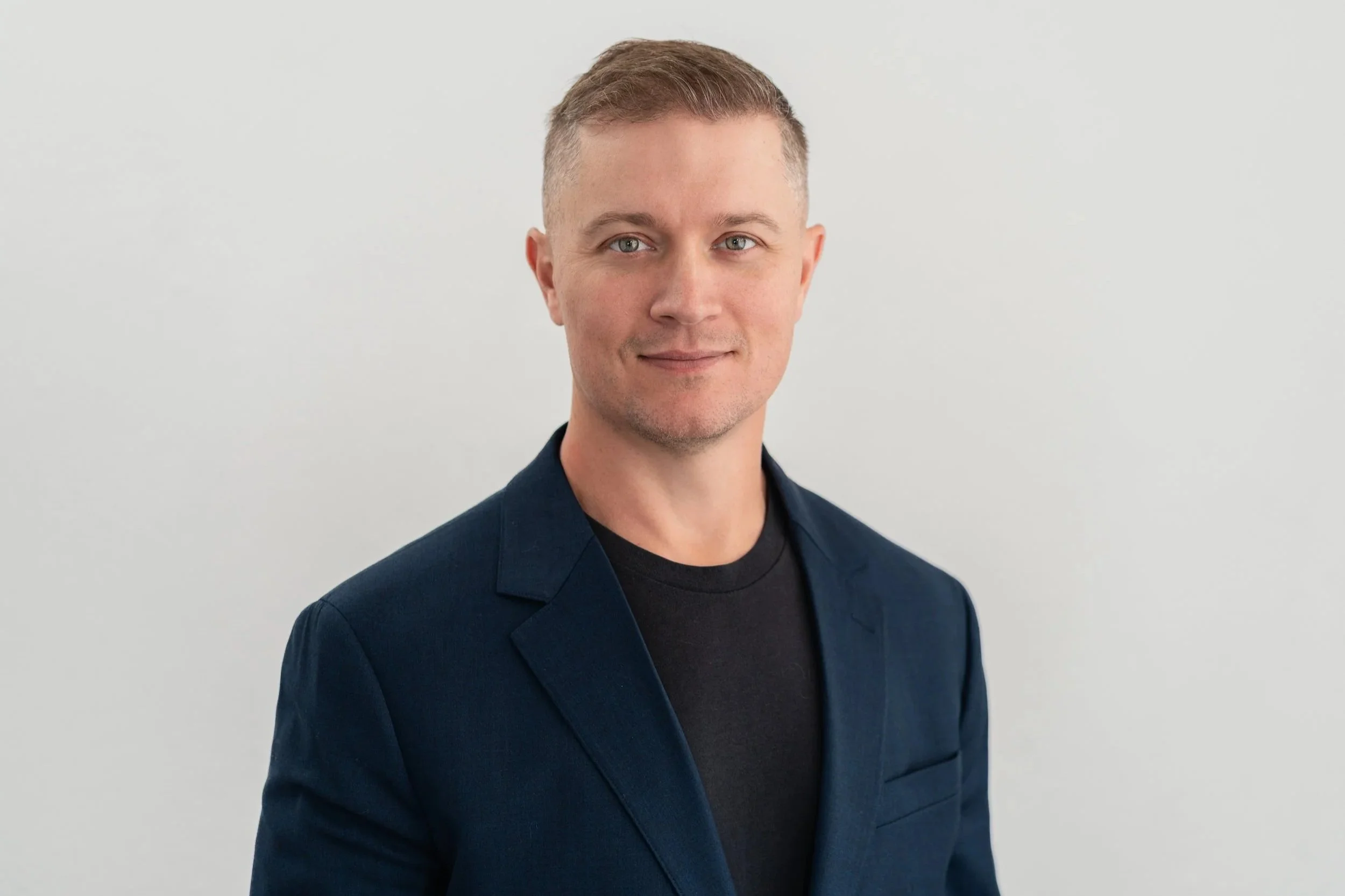 Seattle studio headshot in Greenwood near Ballard. Executive headshot with plain studio backdrop. Man wearing blazer and shirt.