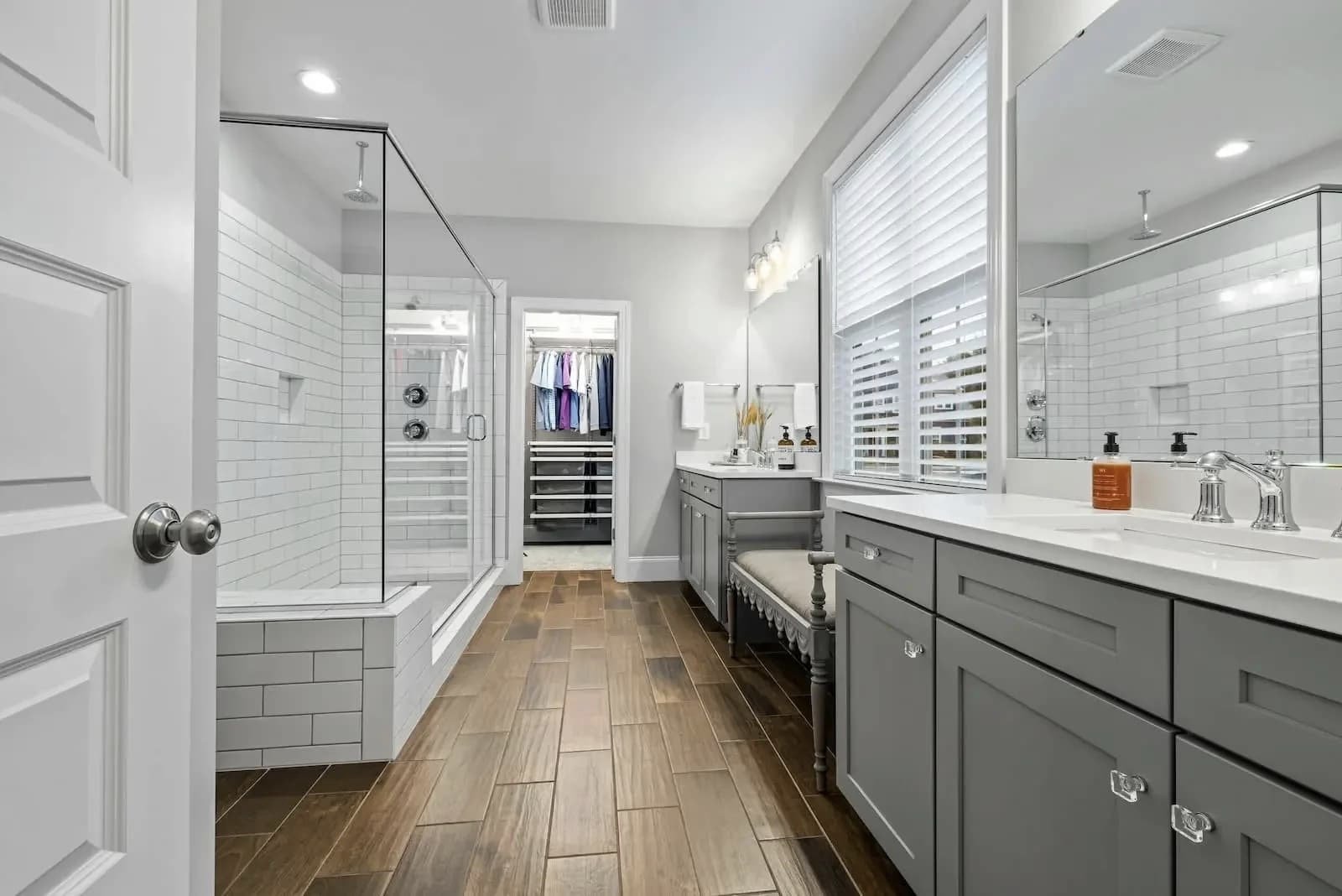 Modern bathroom with gray cabinetry, white subway tile, glass shower enclosure, and wood-look tile flooring in Salem Oregon