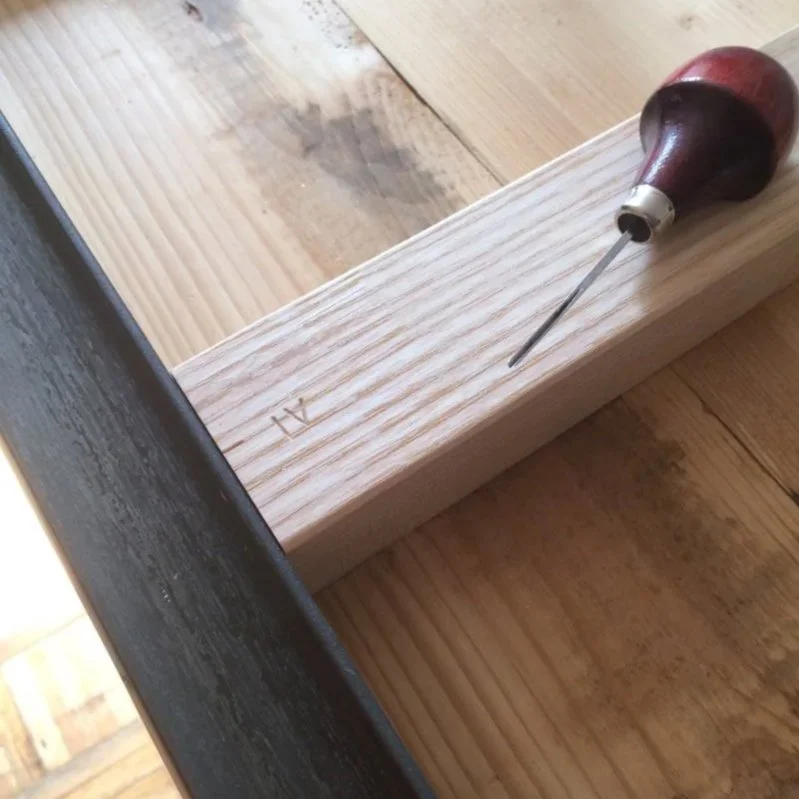 Detail of bespoke furniture being hand-crafted, showing a small chisel carving markings into a solid ash frame, highlighting traditional craftsmanship and bespoke joinery by architects in Bath specialising in heritage and conservation projects.