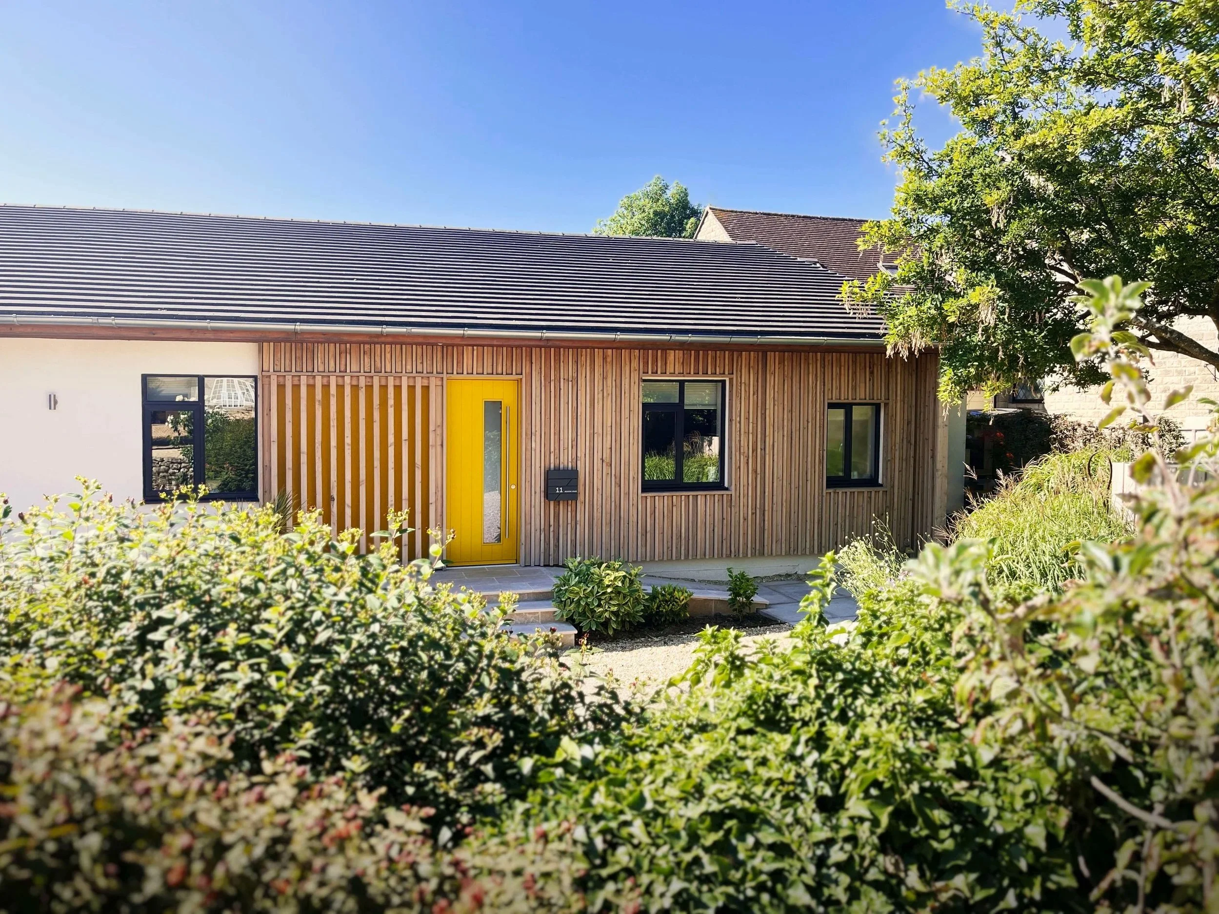 View over hedge from Bradford Road in Winsley towards new larch clad frontage.