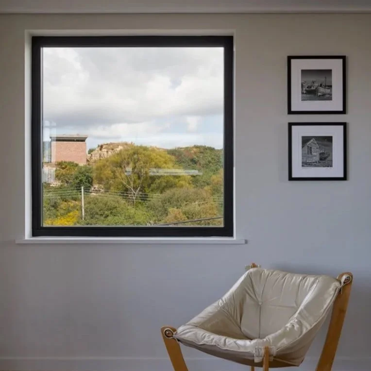 Interior view looking through a window onto a historic landscape, featuring a World War II military tower, highlighting sensitive heritage architecture and conservation by architects in Bath and Kent specialising in listed building projects.