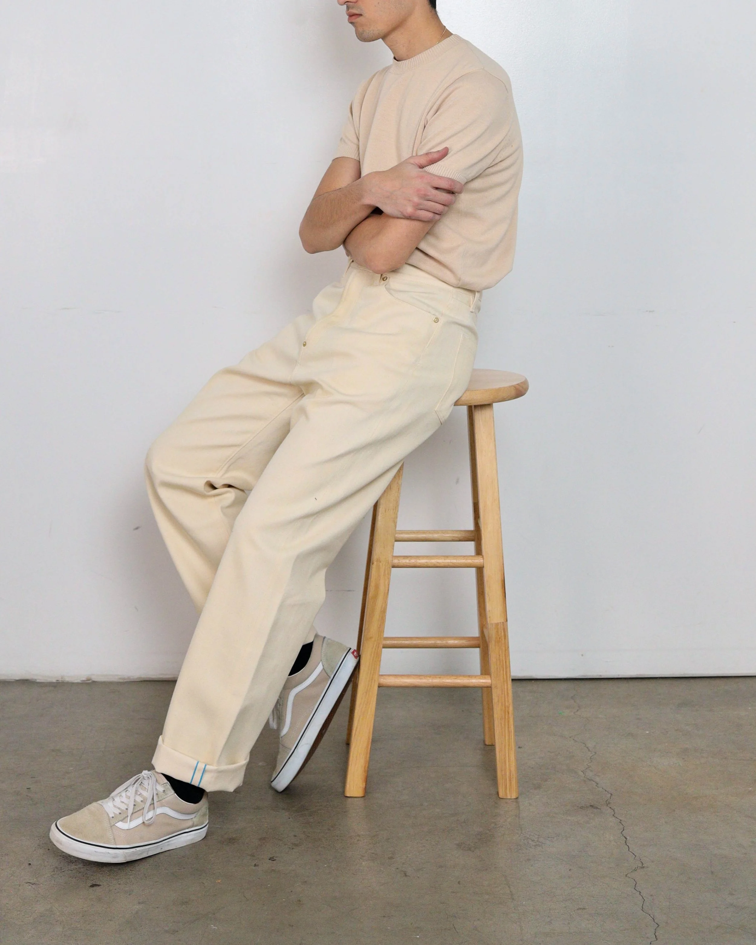 On‑body side view of ecru selvedge denim jeans by [ko’lōn] with a straight‑leg fit..