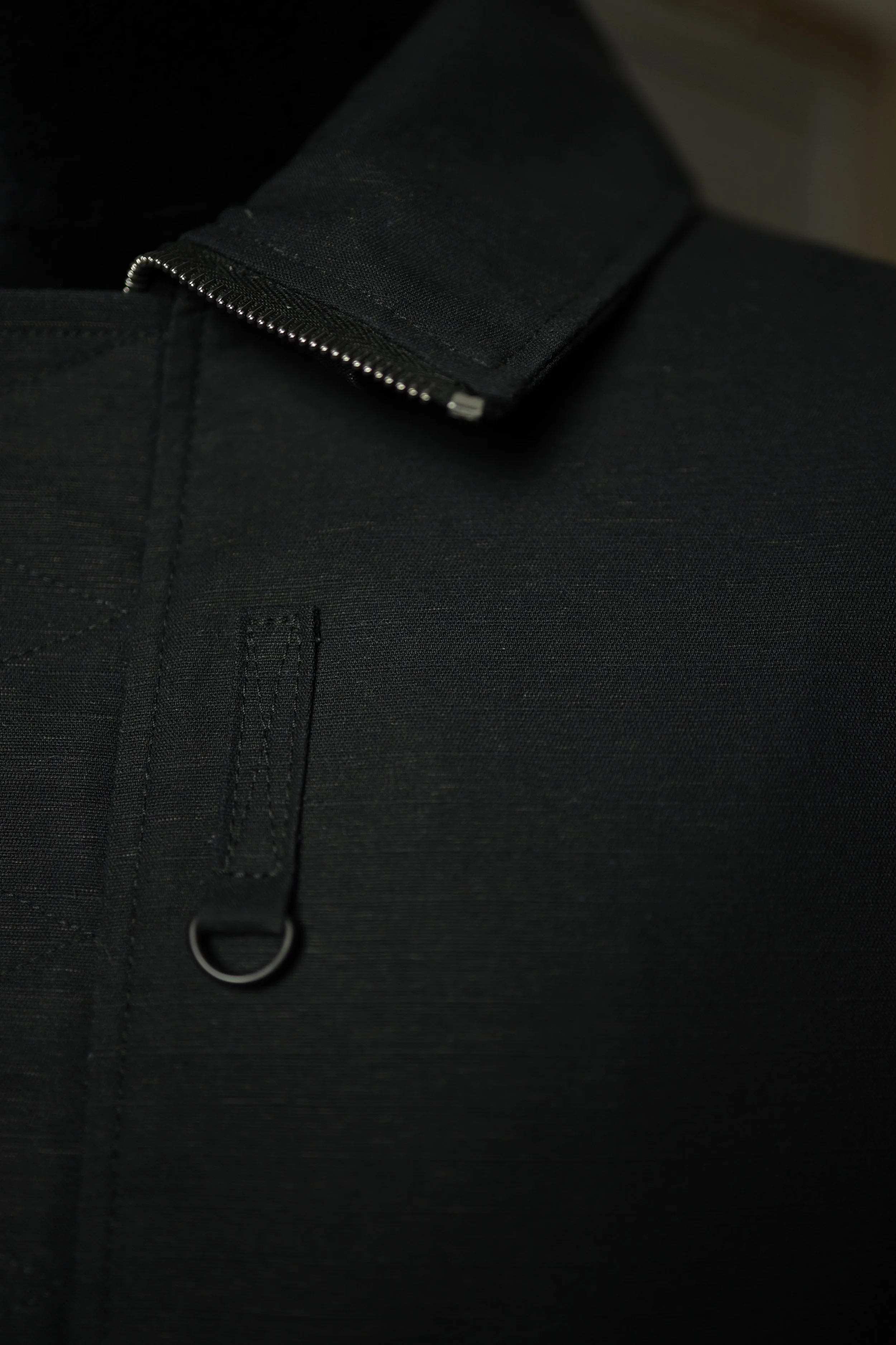 Macro view of black cotton ripstop fabric used in the Navigator Jacket showing texture and weave.