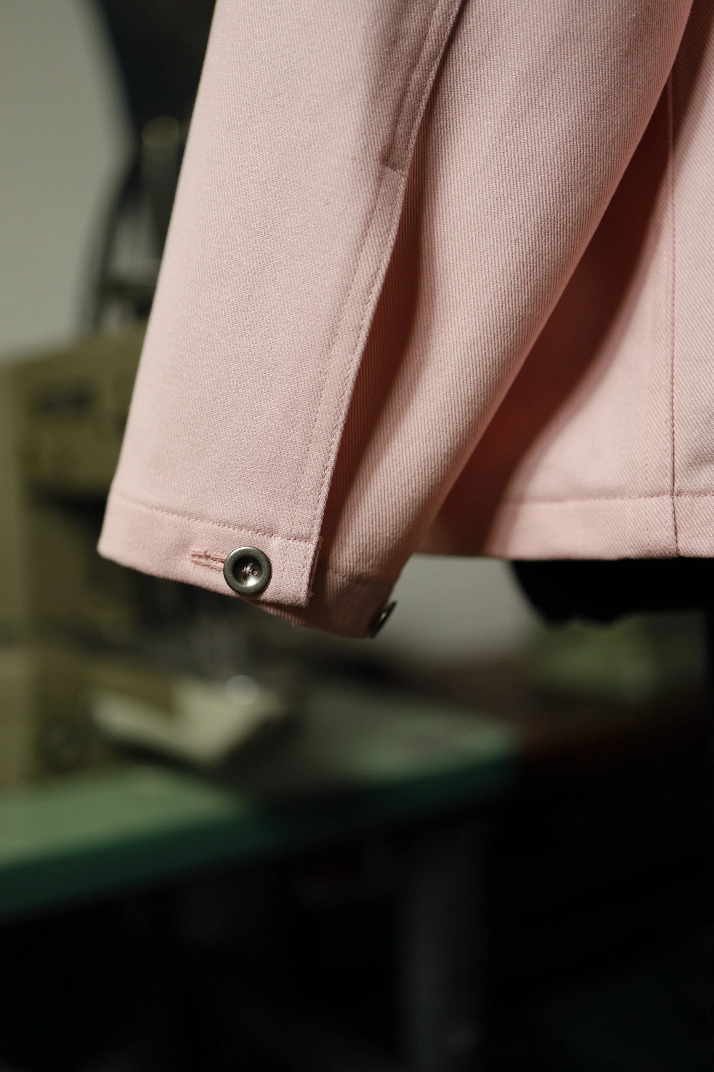Cuff detail of a rose pink cotton denim pullover shirt showing button closure and fine craftsmanship.